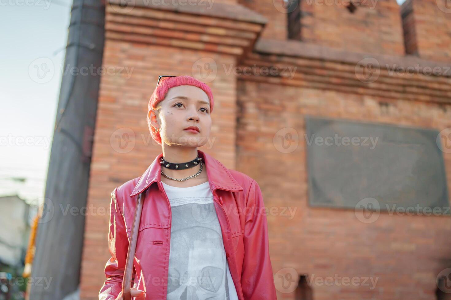 Gen z girl leather fashion with punk Asian woman tourist of local city Southeast Asia travel trendy pink hairstyle young female punk traveler walking in town photo