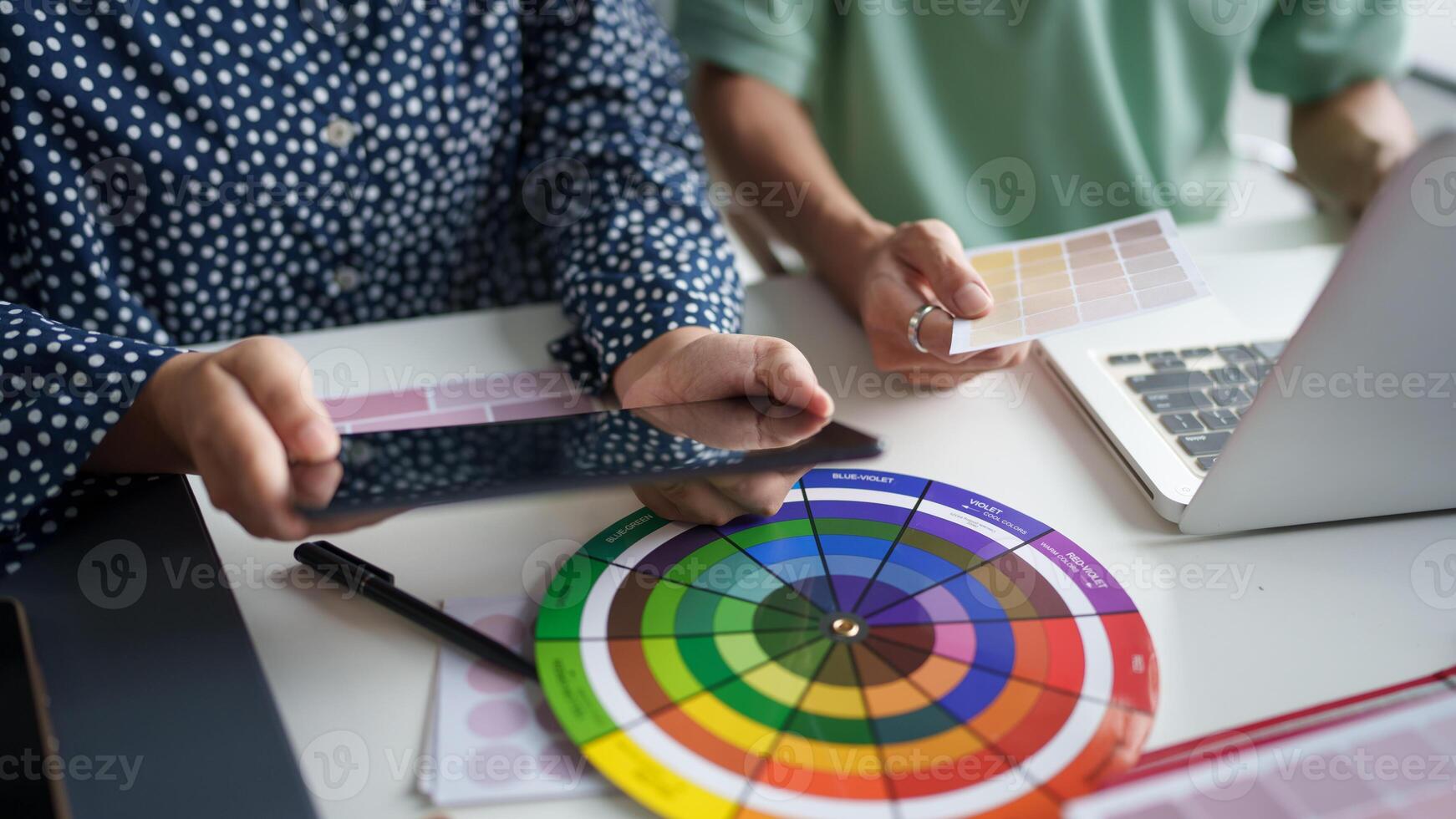 a two person is using a tablet and a color wheel photo