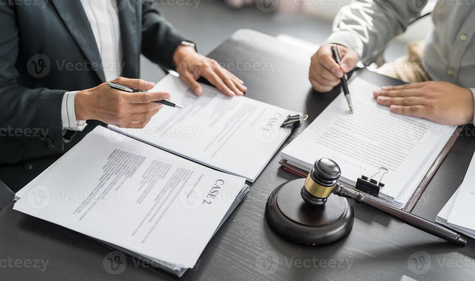 two people sitting at a table with papers and a gavel photo
