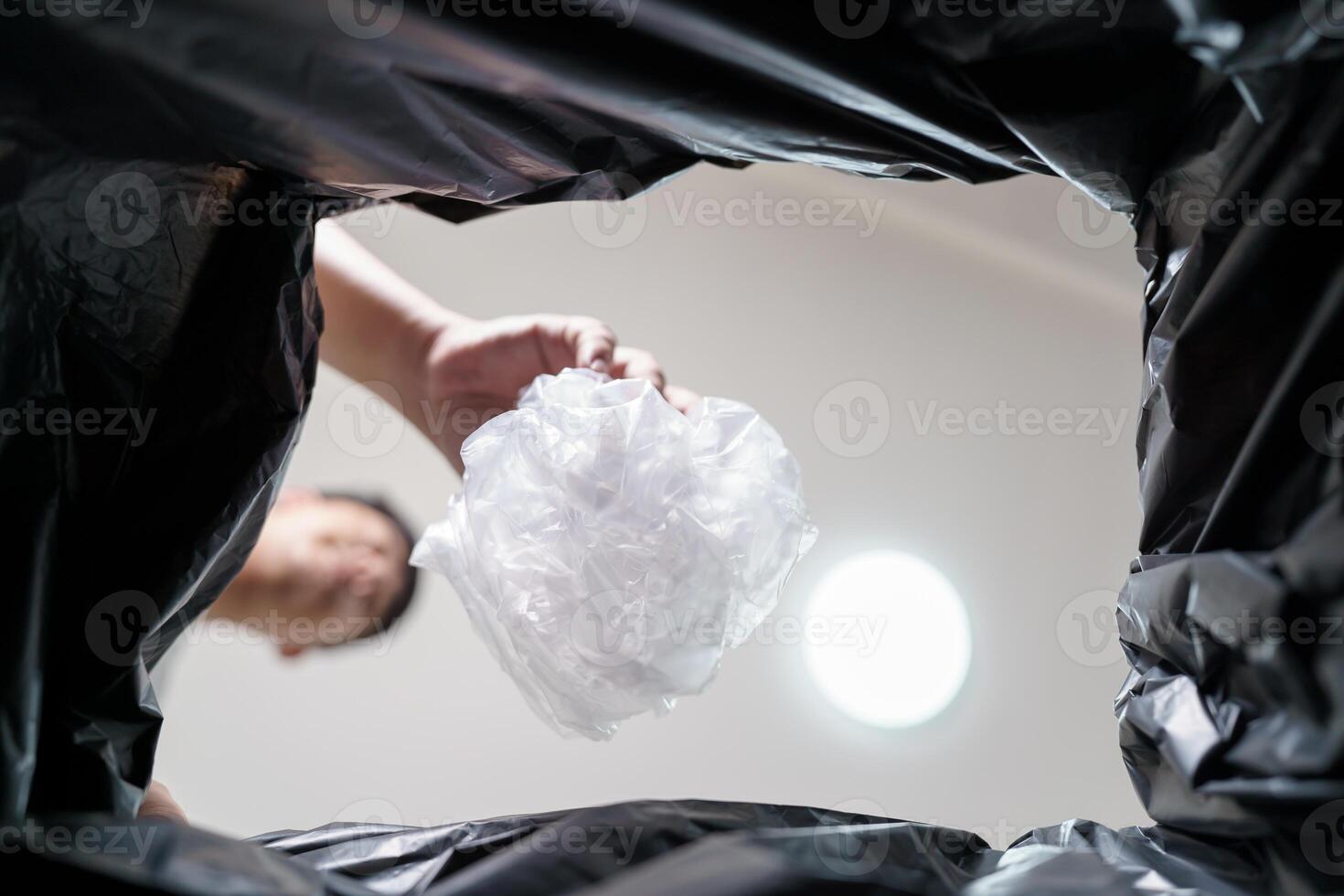 Image from inside yellow recycling bag of man throwing empty plastic bottle in recycling bin Home recycle eco green zero concept photo