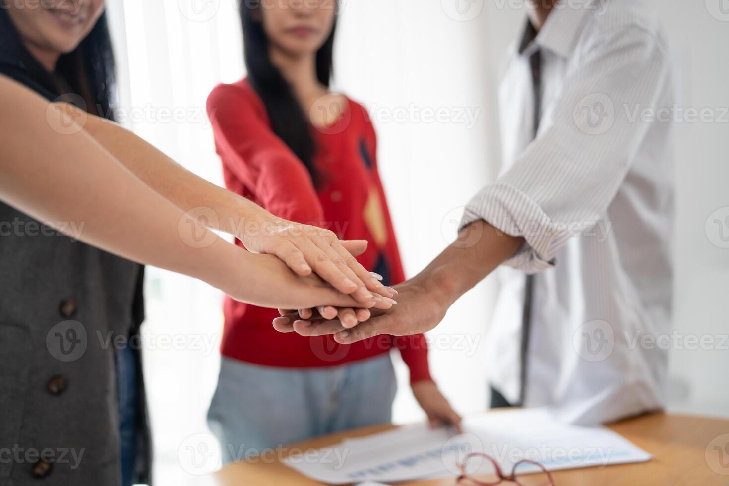 group of Asian business people hands stack unity and support Team fold their hands on each other photo