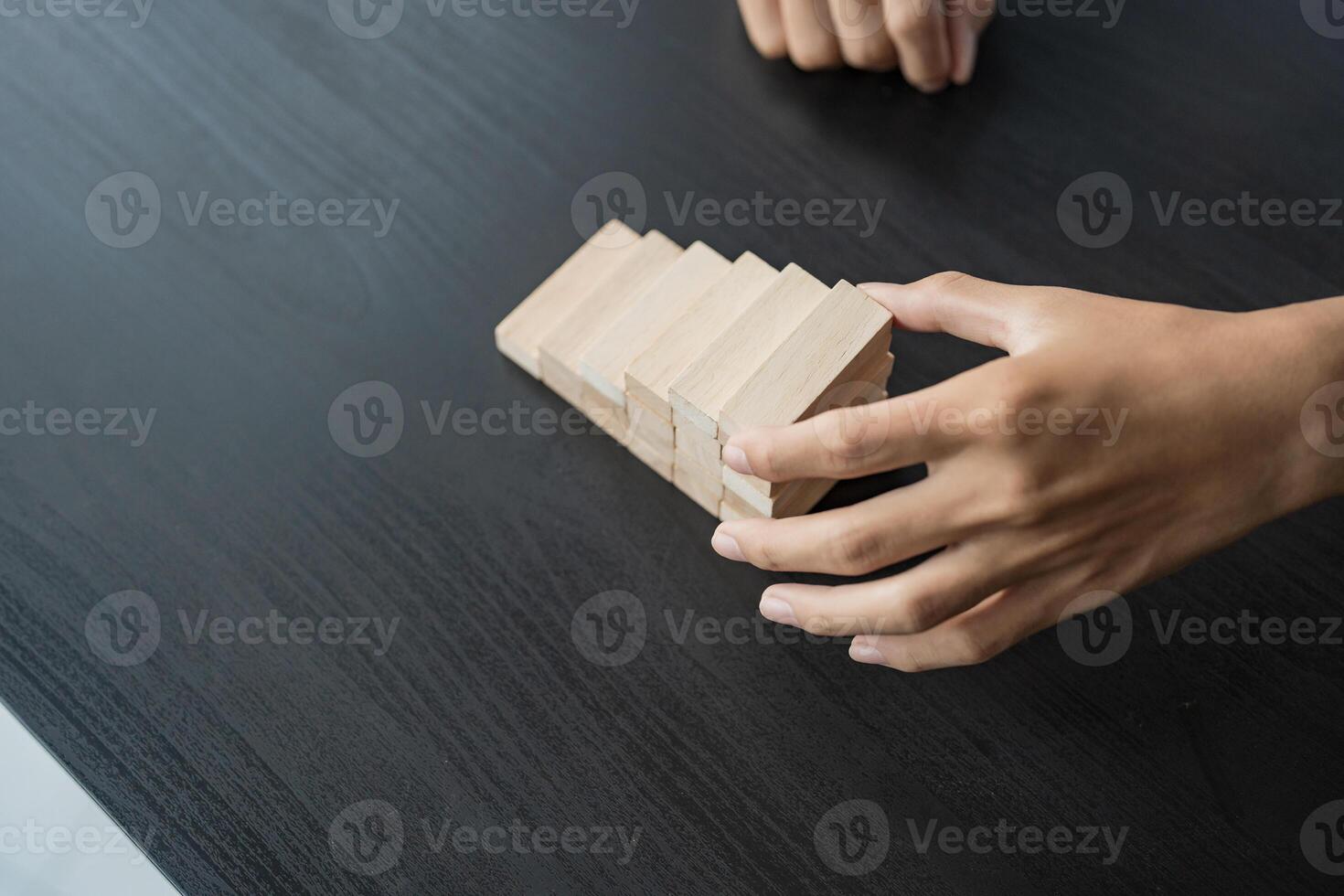 a person is holding a wooden block on a table. photo