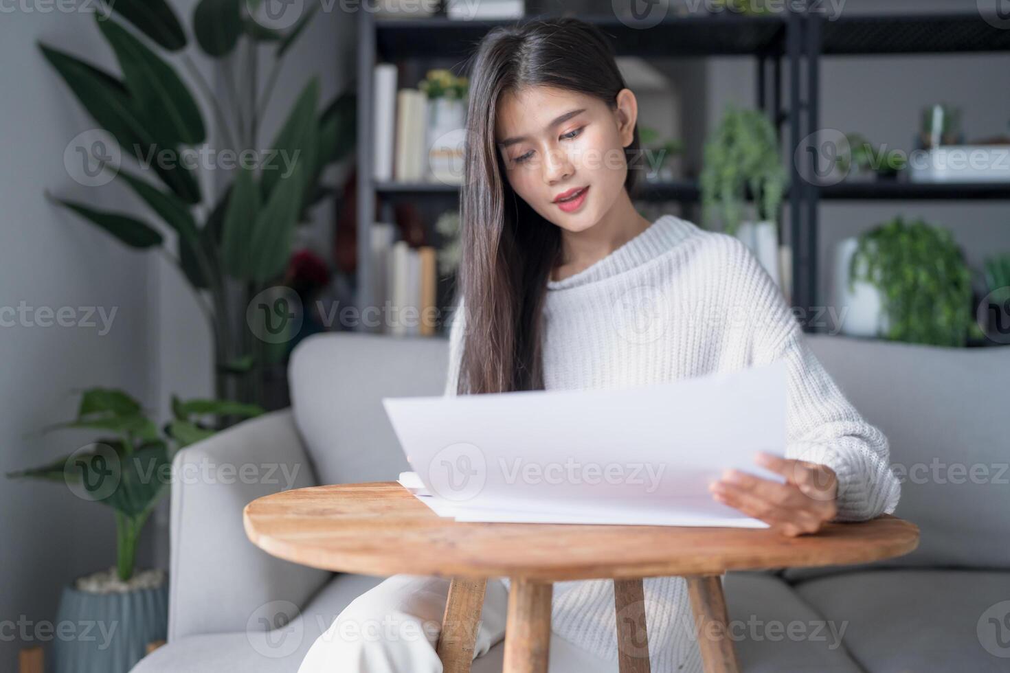 Businesswoman Accountant analyzing investment charts Invoice and pressing calculator buttons over documents. Accounting at home. photo