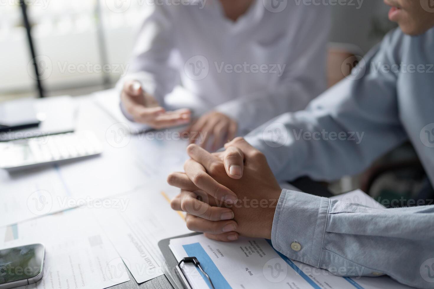 two people sitting at a table with papers and a laptop in office. photo