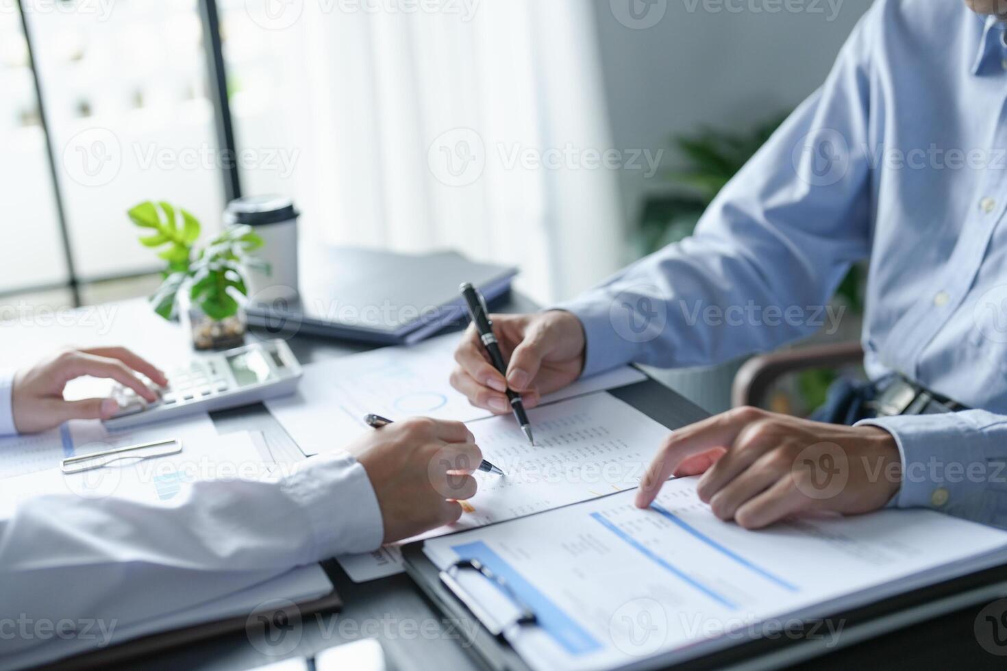two people sitting at a table with papers and pens in office. photo