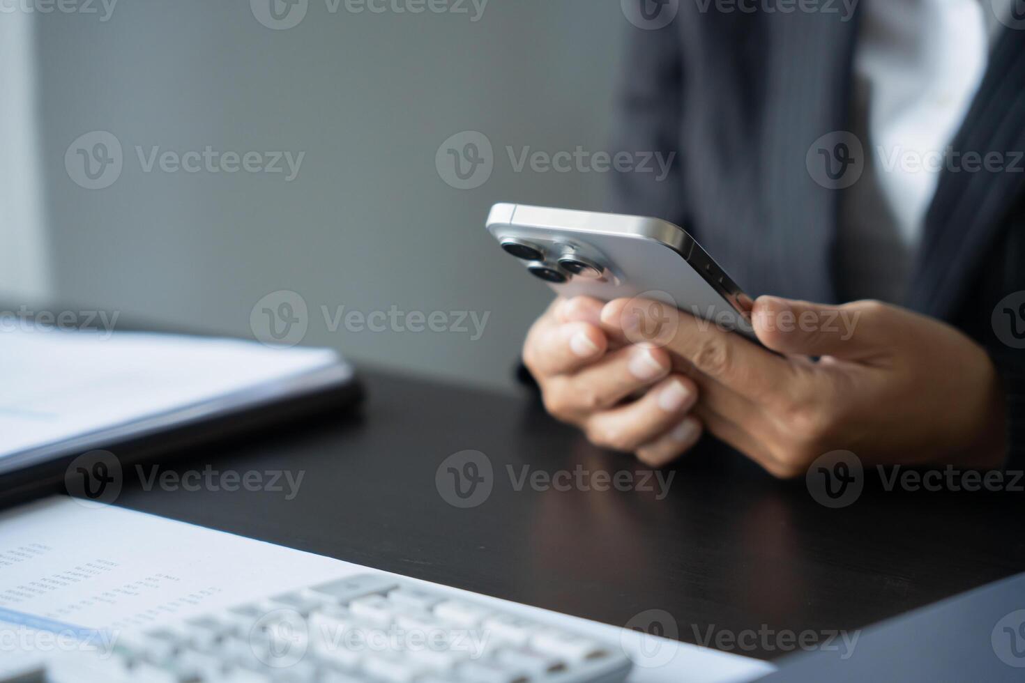 a person sitting at a desk using a cell phone. photo