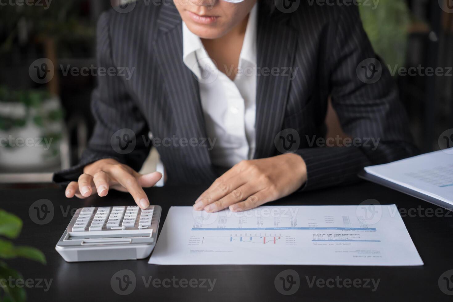a woman in a suit and glasses is using a calculator photo
