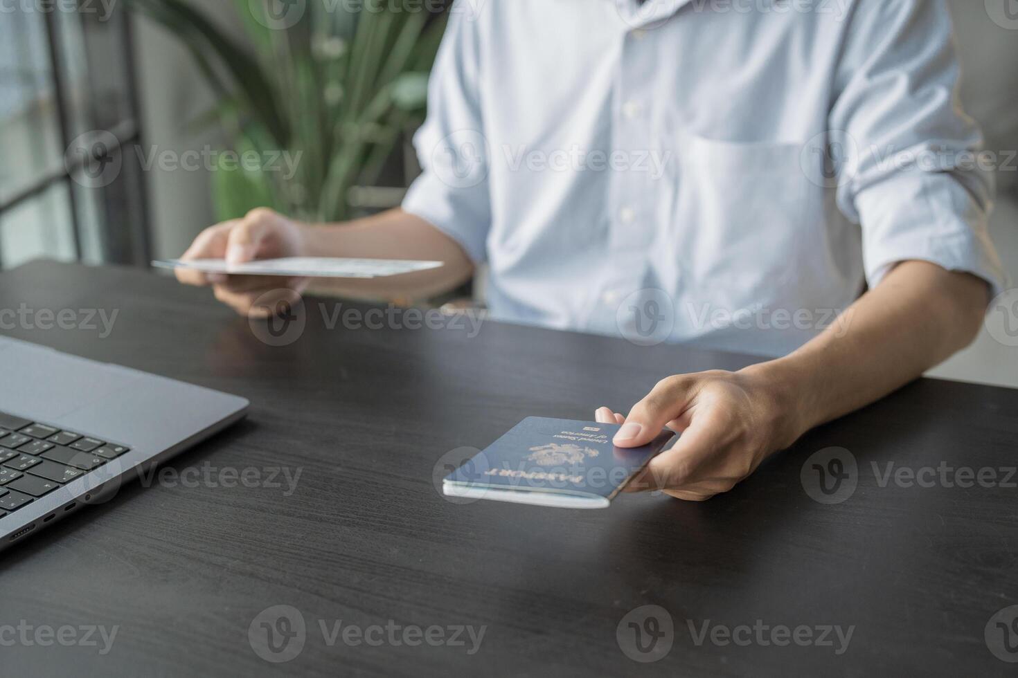 man's hand Online booking and buying plane tickets using laptop phone and credit card Planning trip travel vacation with passport and ticket. photo