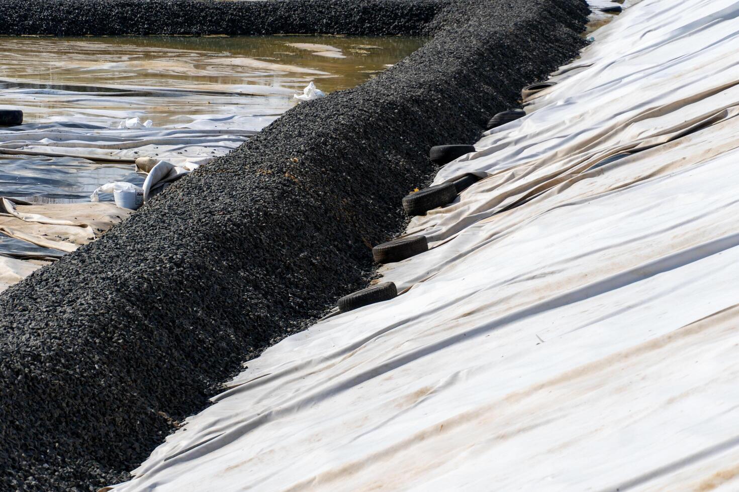 Erosion Control Structure with Aggregate and Used Tires for Slope Stabilization and Sediment Control on White Fabric photo