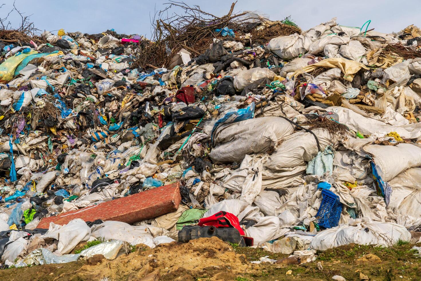 Landfill mountain showcases waste management issues with mixed refuse, plastic bags, and environmental pollution concerns. photo
