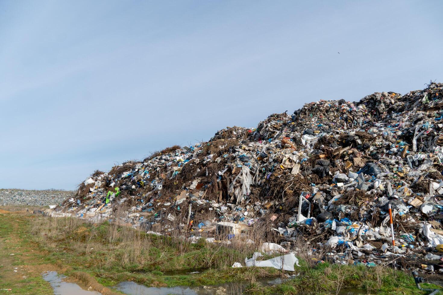 Landfill Overflowing with Trash and Debris Under Blue Sky, Illustrating Environmental Pollution and Waste Management Issues photo