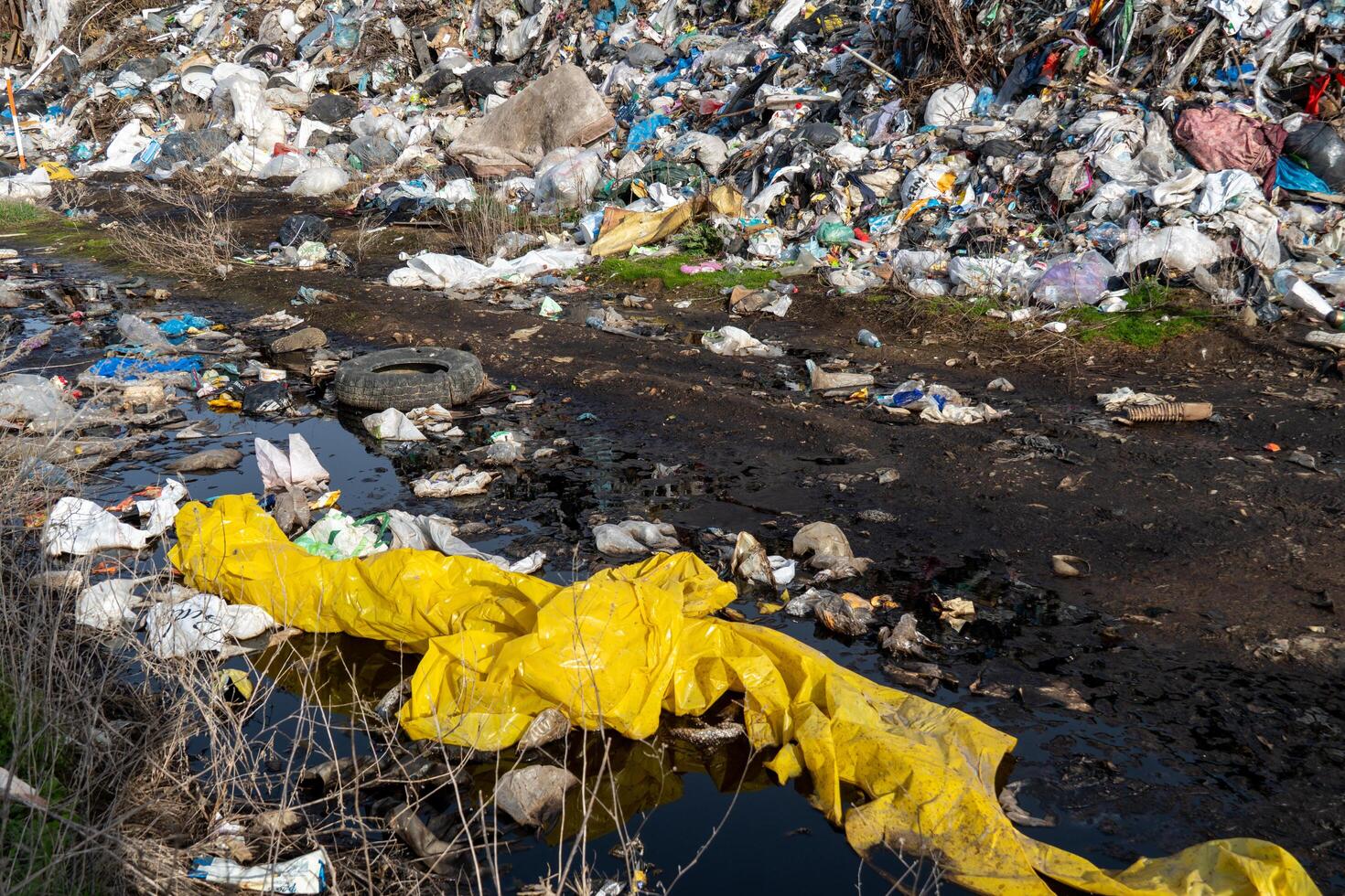 Large Landfill Polluting a Waterway, Overflowing with Discarded Plastics and Waste Materials, Causing Severe Environmental Damage photo