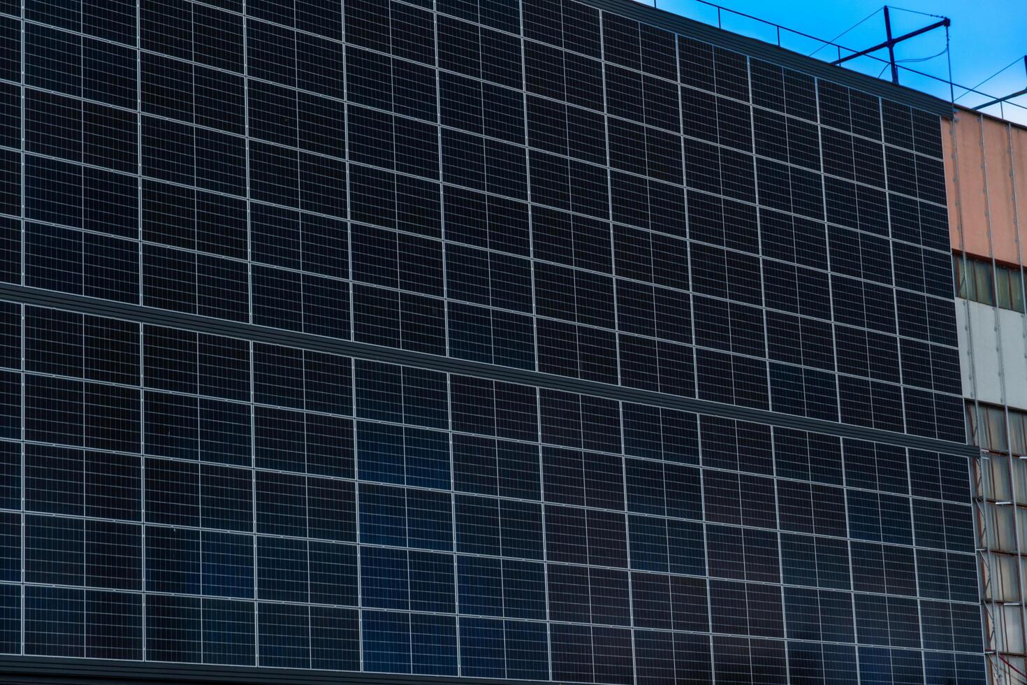 Array of Photovoltaic Cells Covering Exterior Wall for Sustainable Energy Generation with Cloudy Sky and Building Structure photo