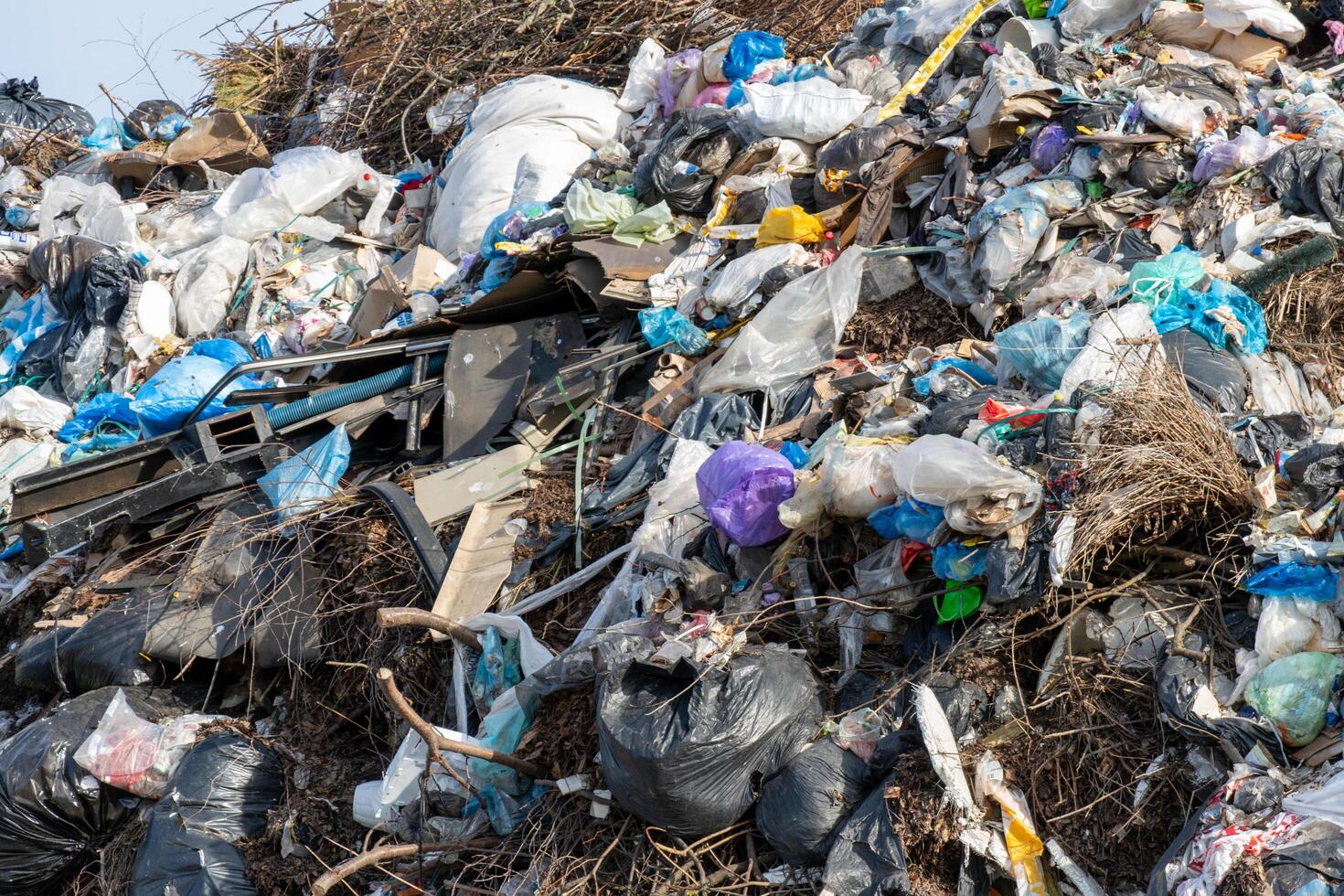 Massive pile of discarded refuse featuring a mixture of plastic bags, construction debris, and scattered organic matter photo