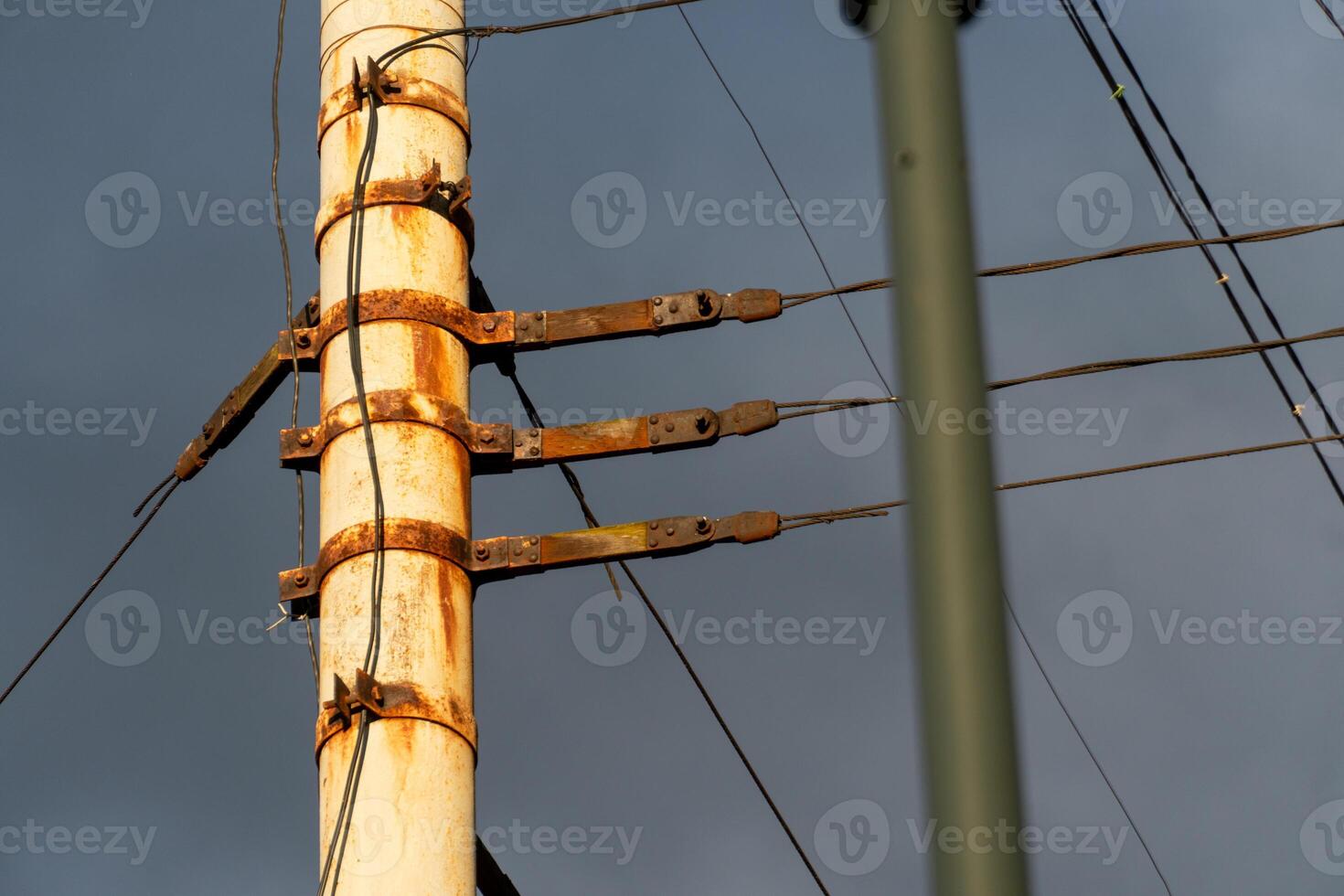Utility Pole with Rust and Weathered Cables Against Gray Sky photo