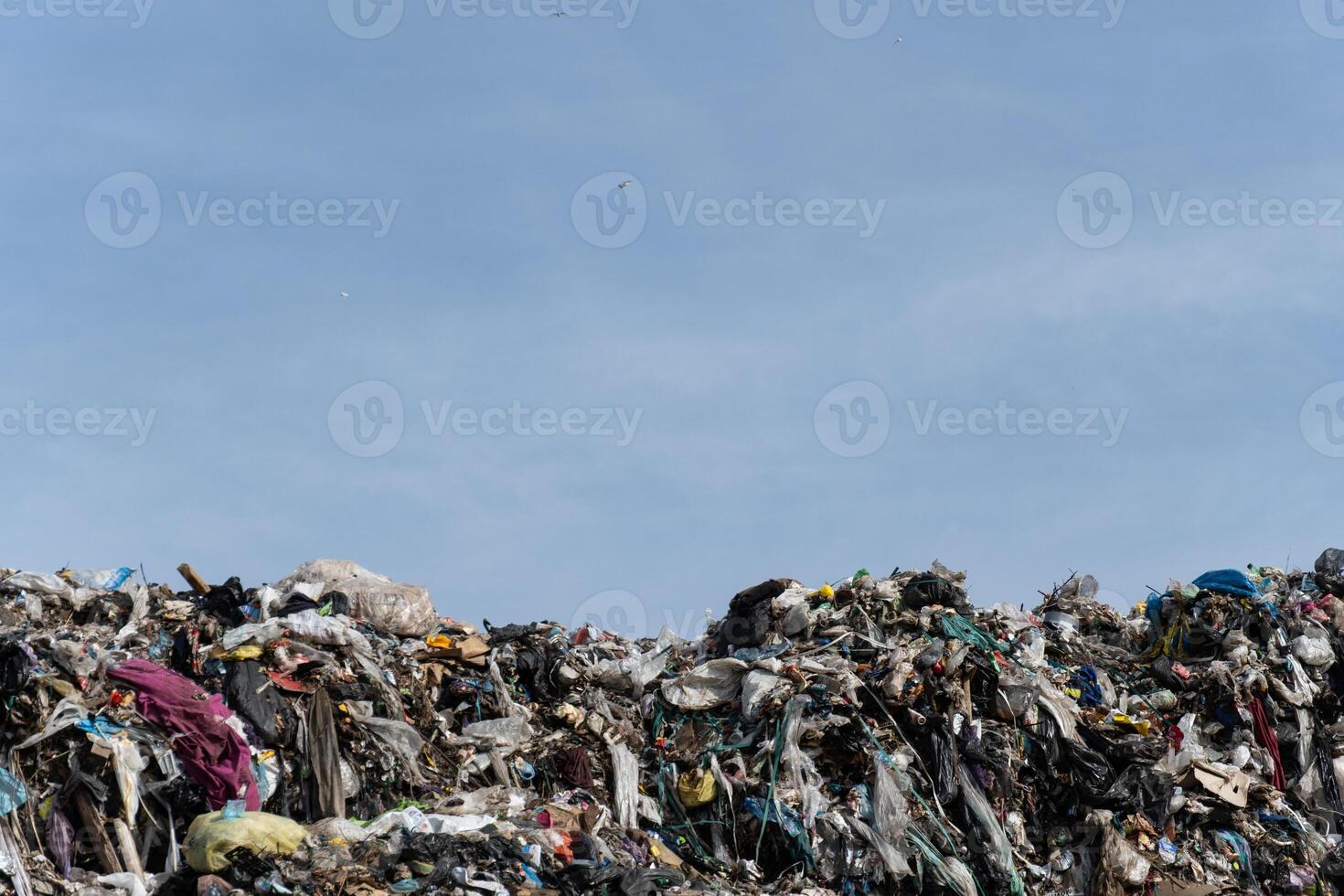 Large Mountain of Discarded Waste Materials at Landfill Under Open Blue Sky photo