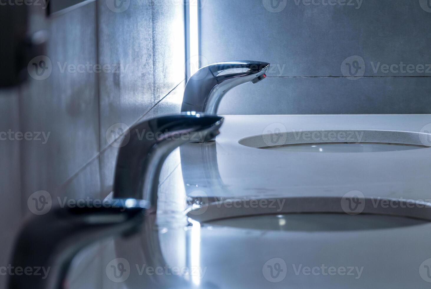 Sleek faucets are shown in a stylish restroom featuring polished surfaces and a minimalist aesthetic, creating a contemporary and clean atmosphere photo