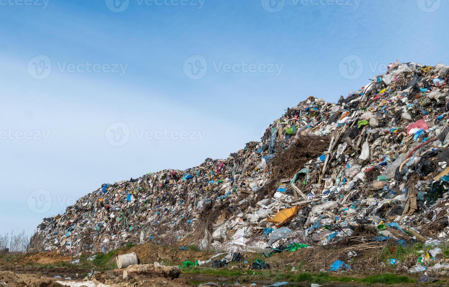 A large landfill showcases heaps of colorful plastic waste and debris under a clear blue sky, emphasizing pressing environmental concerns photo