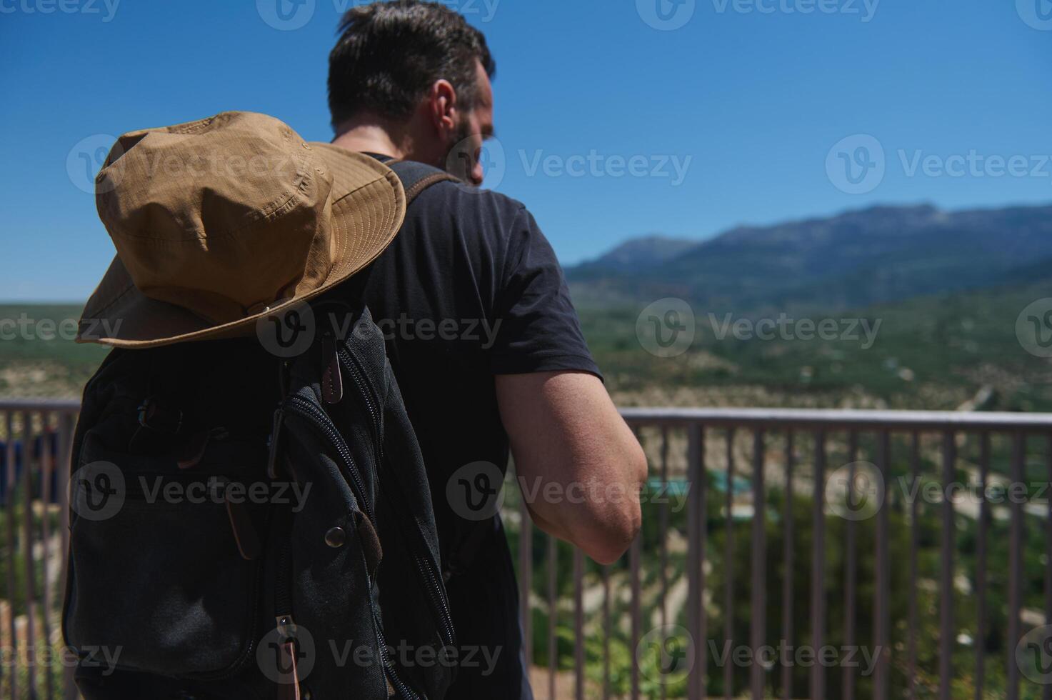 Traveler Exploring Scenic Mountain Views with Backpack and Hat on a Sunny Day photo