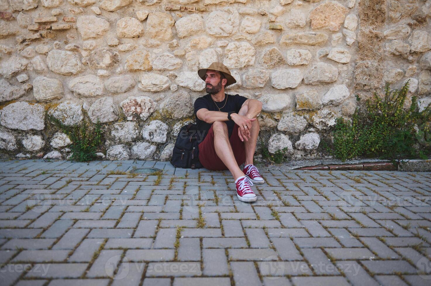 Backpack Traveler Sitting Against Brick Wall, Embracing Adventure photo