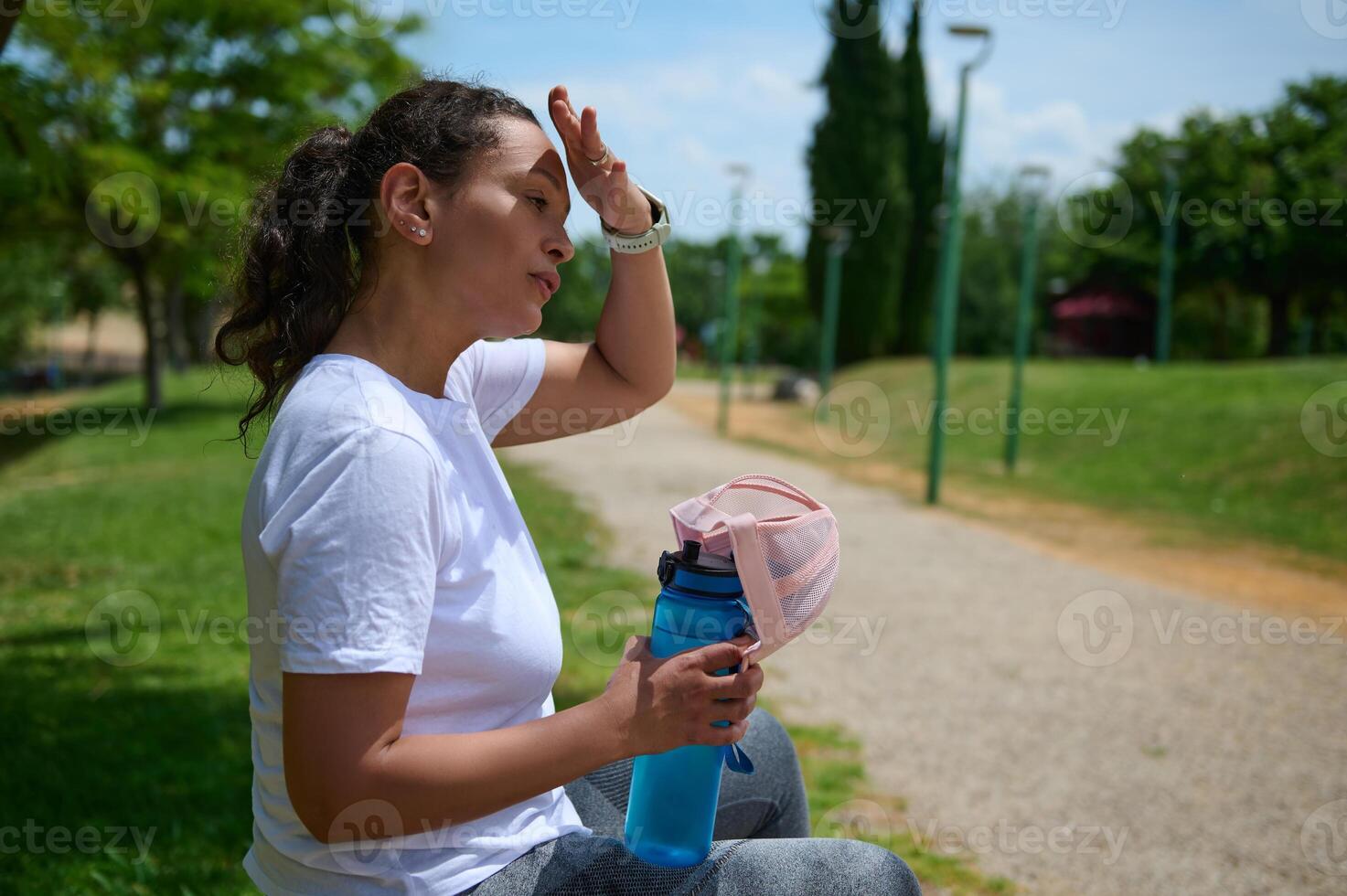 Woman Resting Outdoors with Water Bottle in Park Setting photo