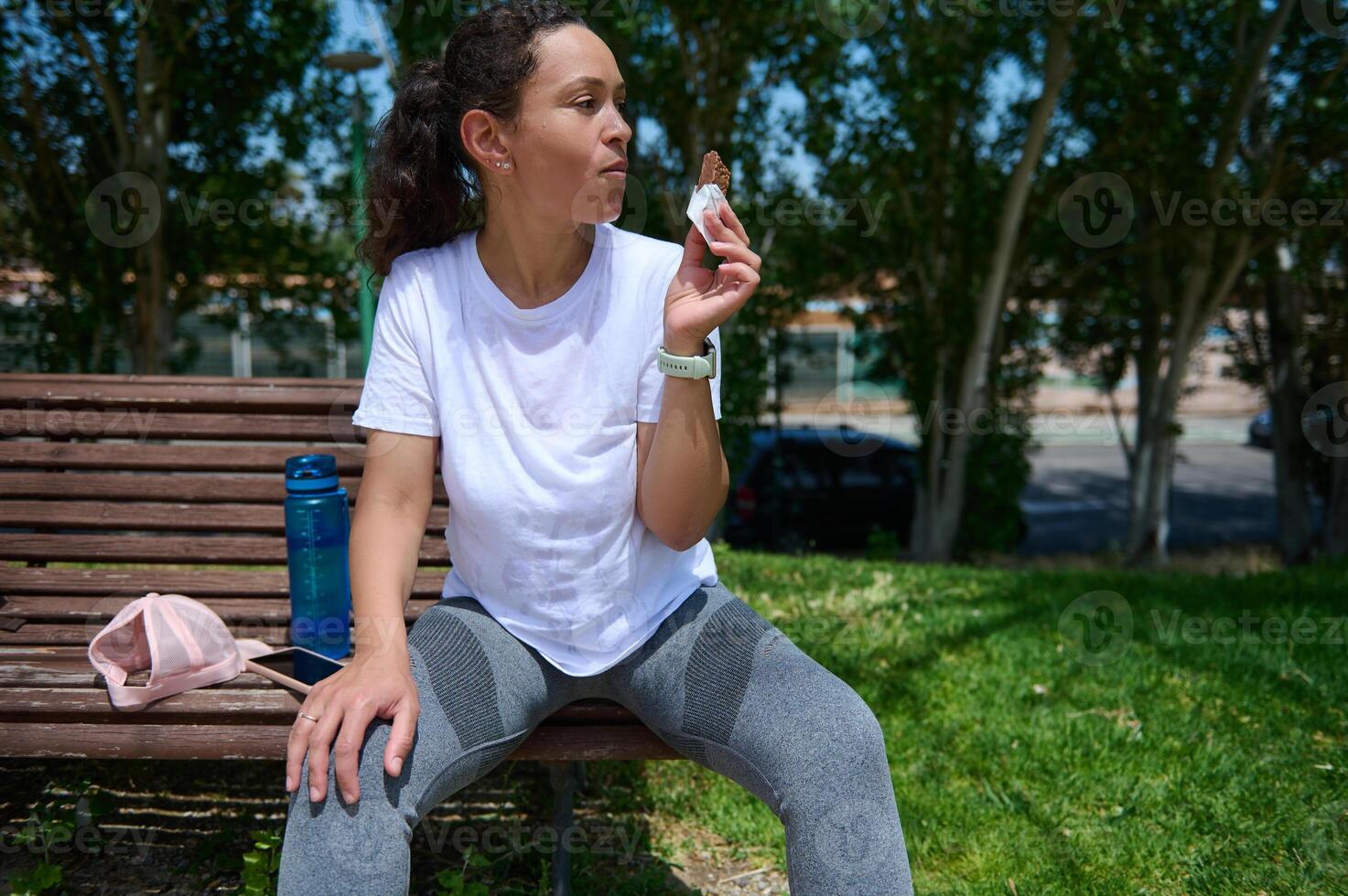 Woman Resting on Park Bench Enjoying a Snack After Outdoor Workout photo