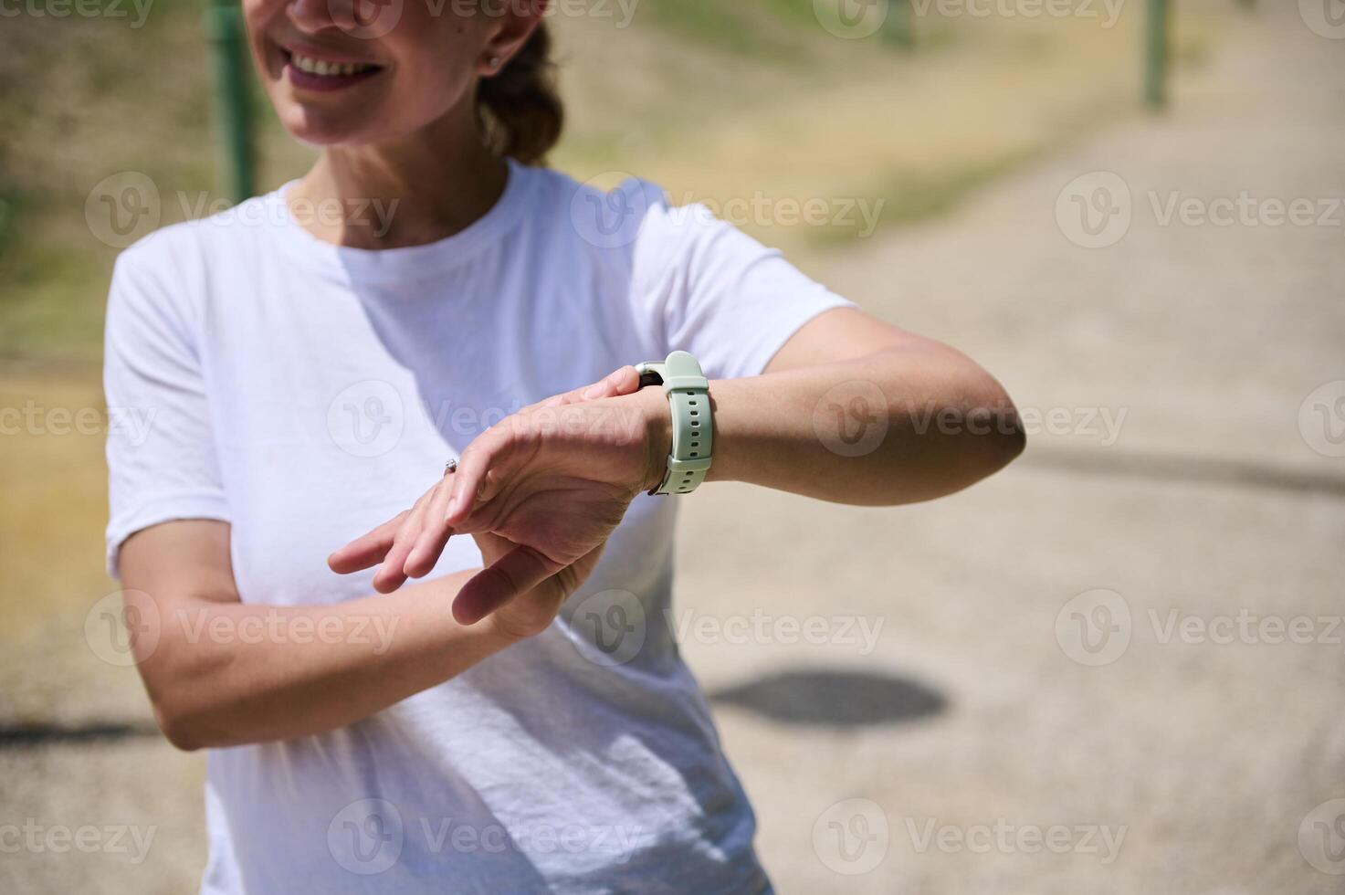 Woman Checking Fitness Tracker on Park Trail in Bright Daylight photo