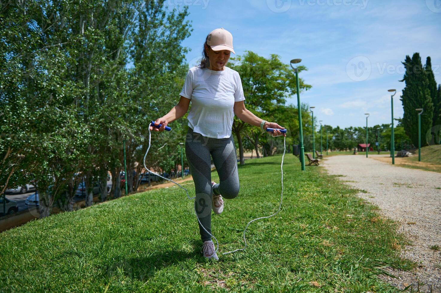 Young Woman in Activewear Skipping Rope in Park on Sunny Day photo