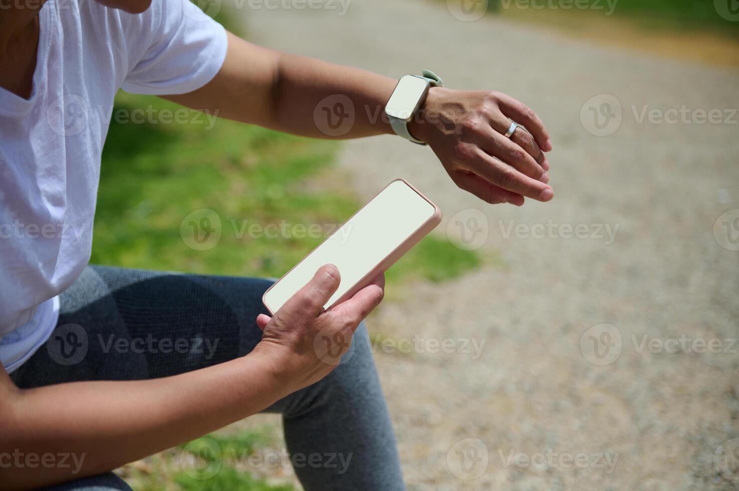 Active Woman Using Mobile Phone and Smartwatch Outdoors in a Sunny Park Setting photo