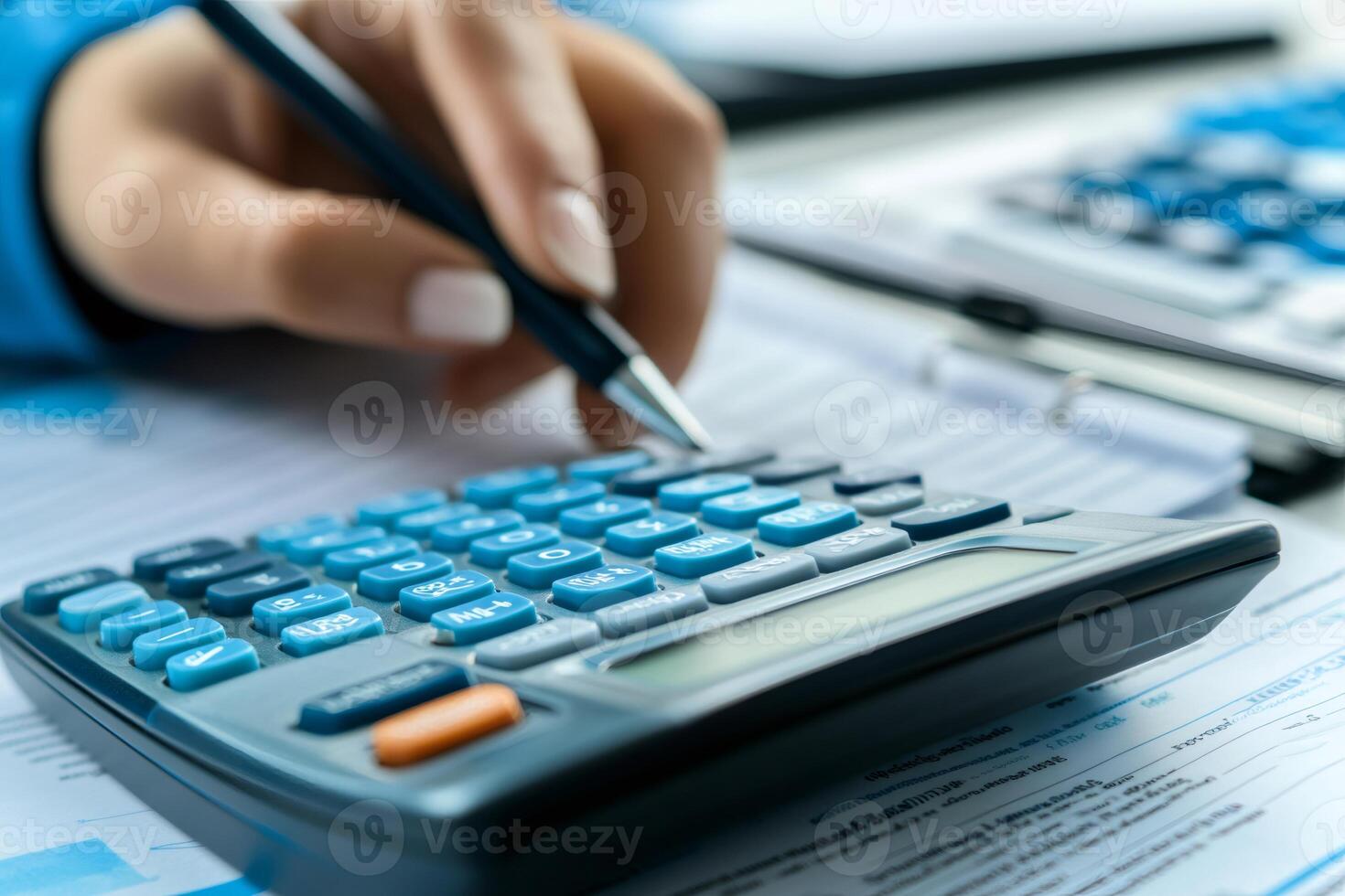 Accountant calculating tax using calculator and pen on desk photo