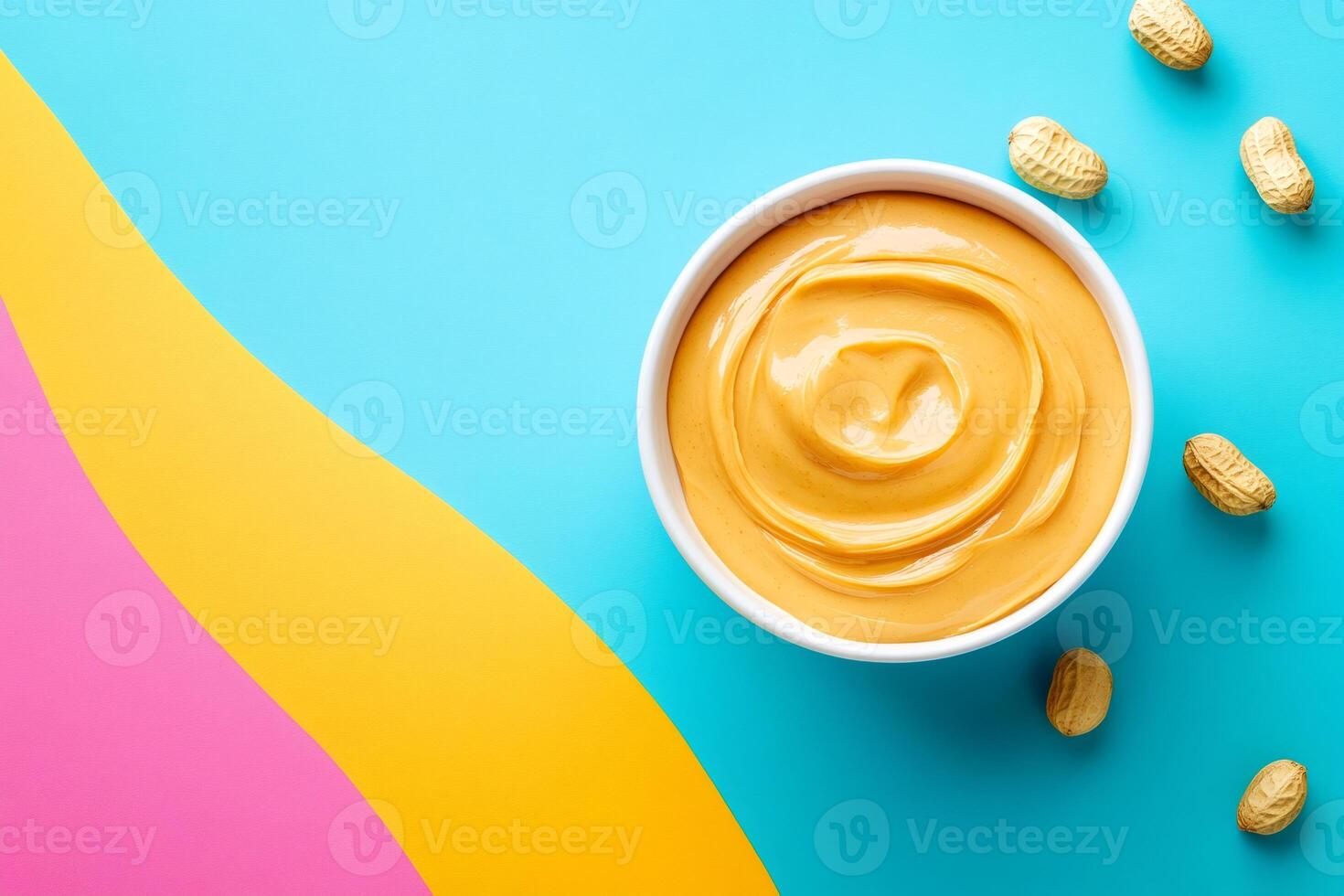 Creamy peanut butter in bowl on vibrant blue background with peanuts photo