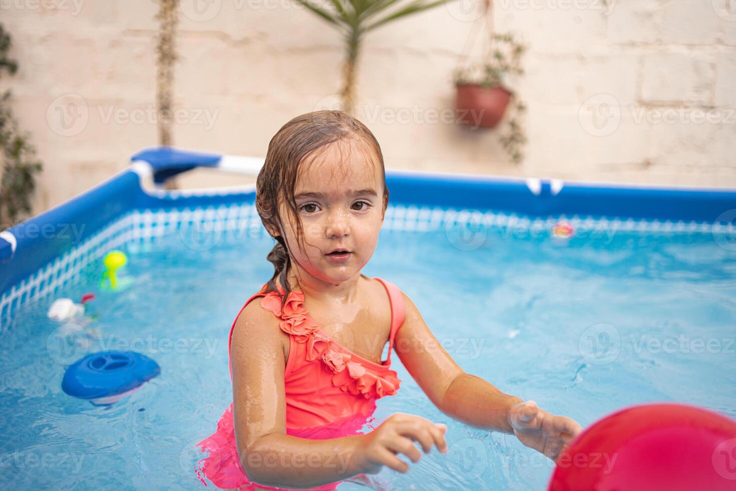 Young girl enjoys playtime in backyard pool with colorful toys photo