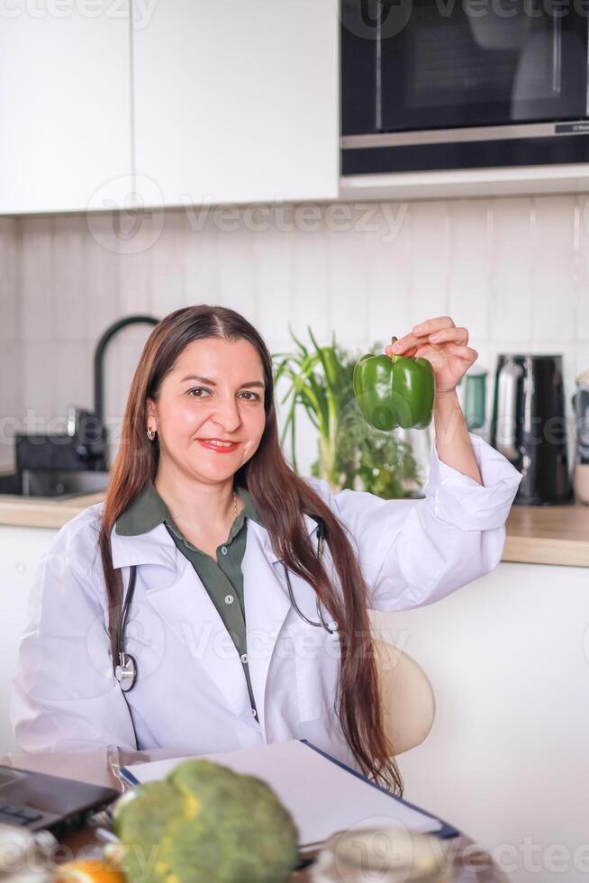Nutritionist doctor holding green pepper, health benefits of eating fresh vegetables. Diet, eating behavior. photo