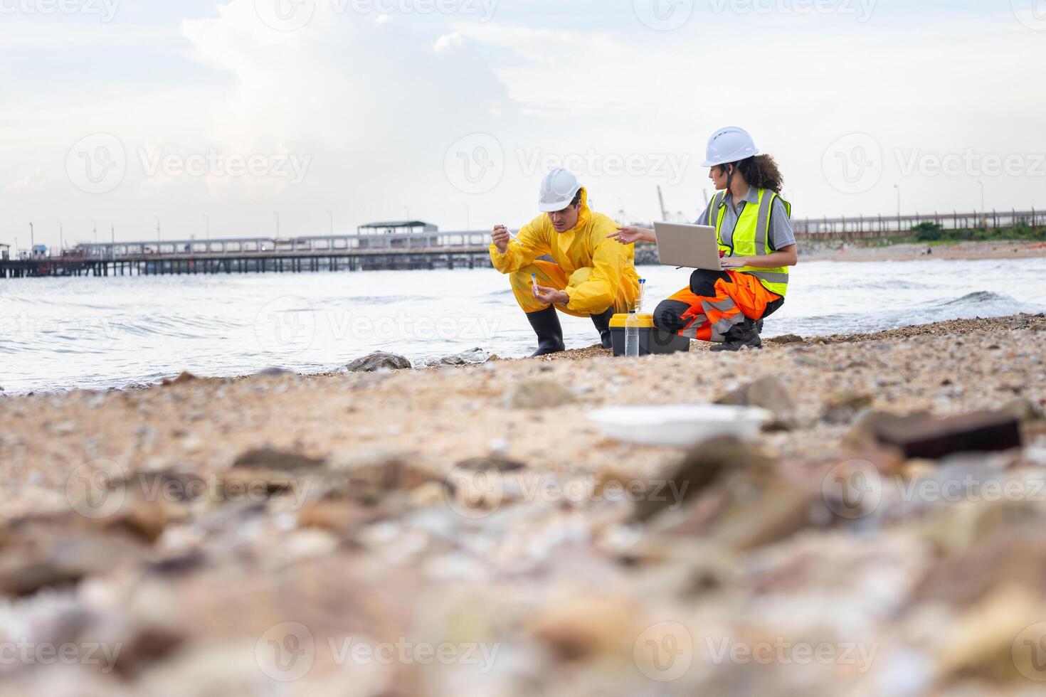 Environmental Engineers Conducting Field Work for Pollution Control, Engineers Analyzing Environmental Data on a Beach Cleanup Project, Workers Collecting Water Samples for Environmental Research photo