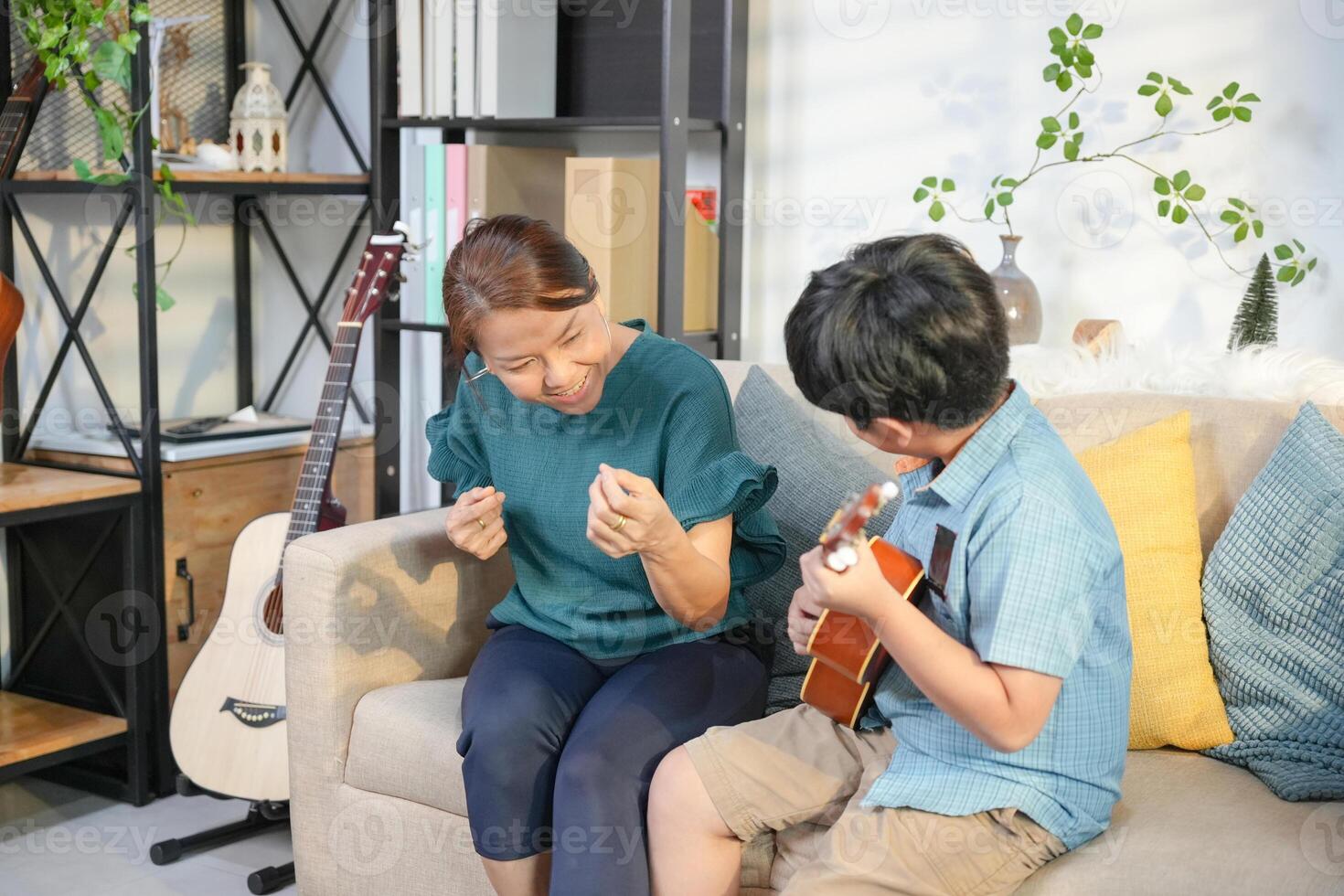 Mother and Son Enjoying Music Together at Home, Boy Playing Ukulele for His Cheerful Grandma photo