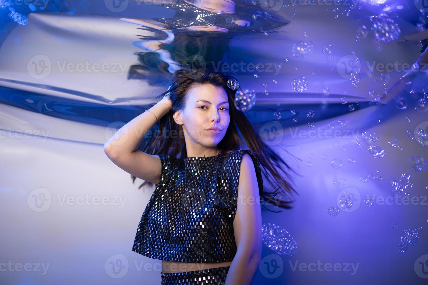 Girl in Sparkling Mermaid Outfit Submerged in Water With Vibrant Bubbles Around Her photo