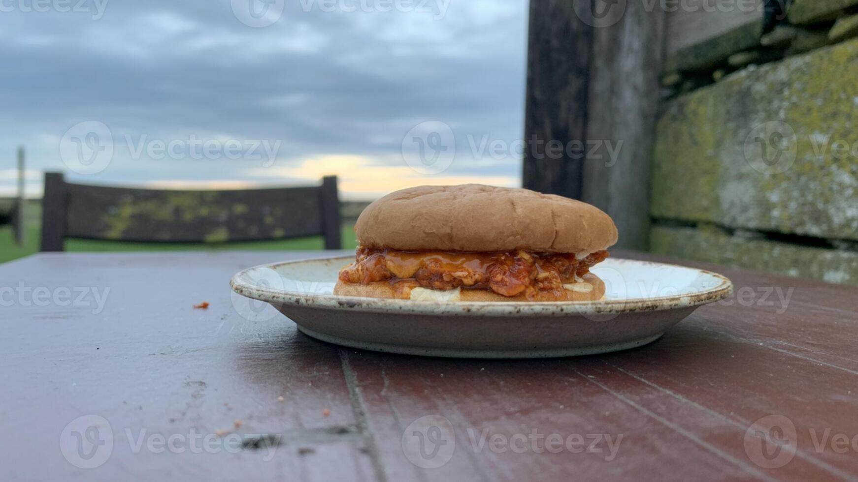 A sandwich sitting on a plate on a wooden table photo