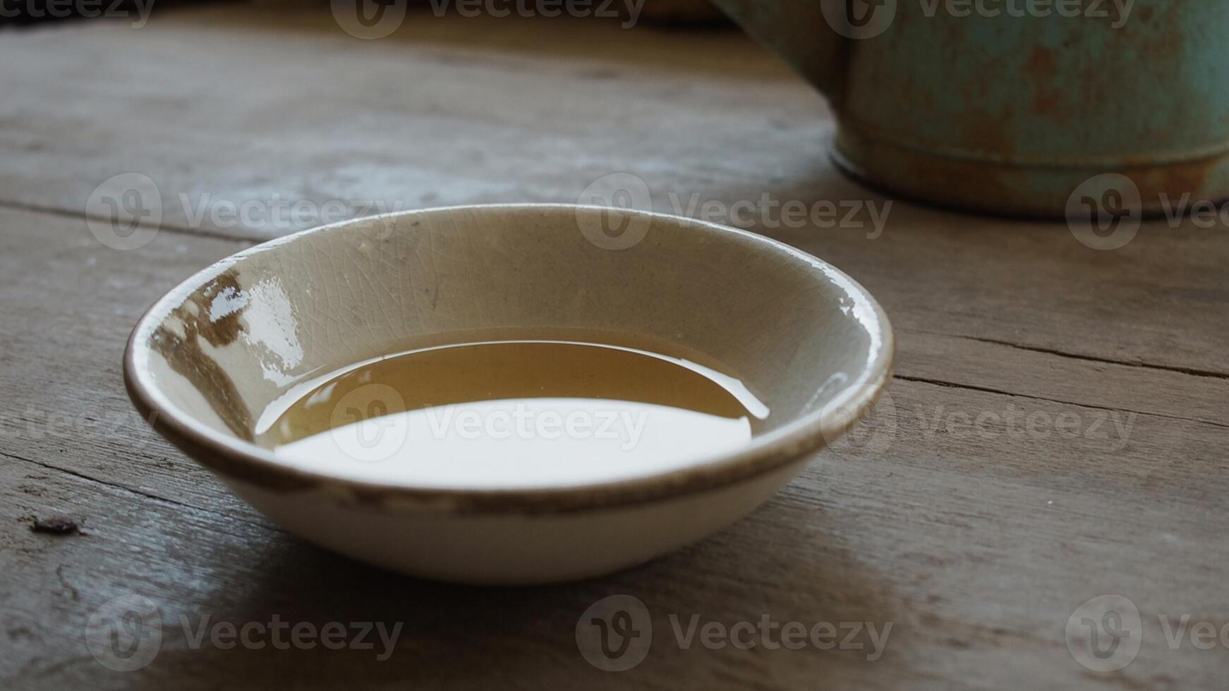 A bowl of water sits on a table next to a teapot photo
