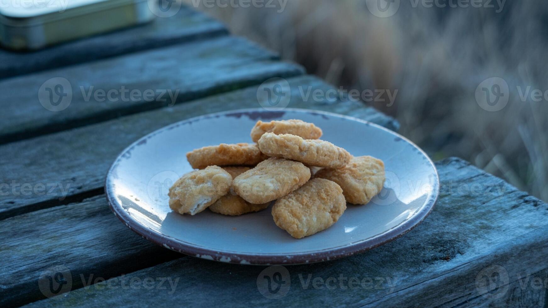 A plate of fried chicken nuggets sitting on a wooden table photo