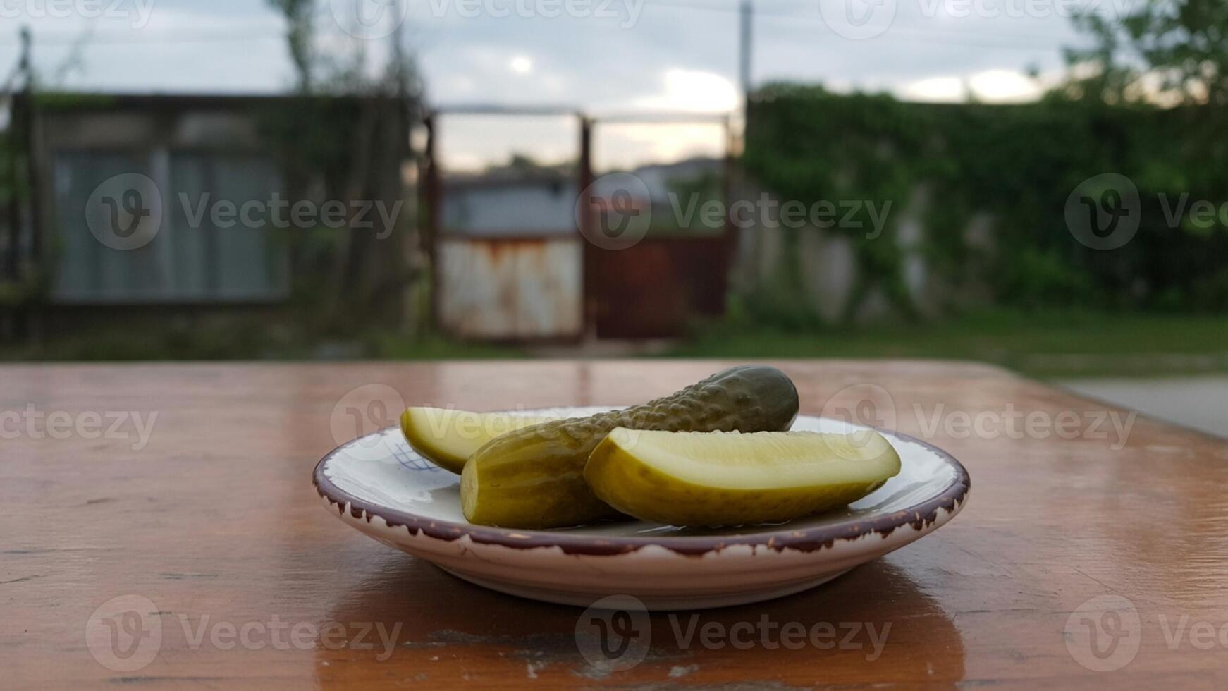 A bowl of pickles on a table in front of a house photo