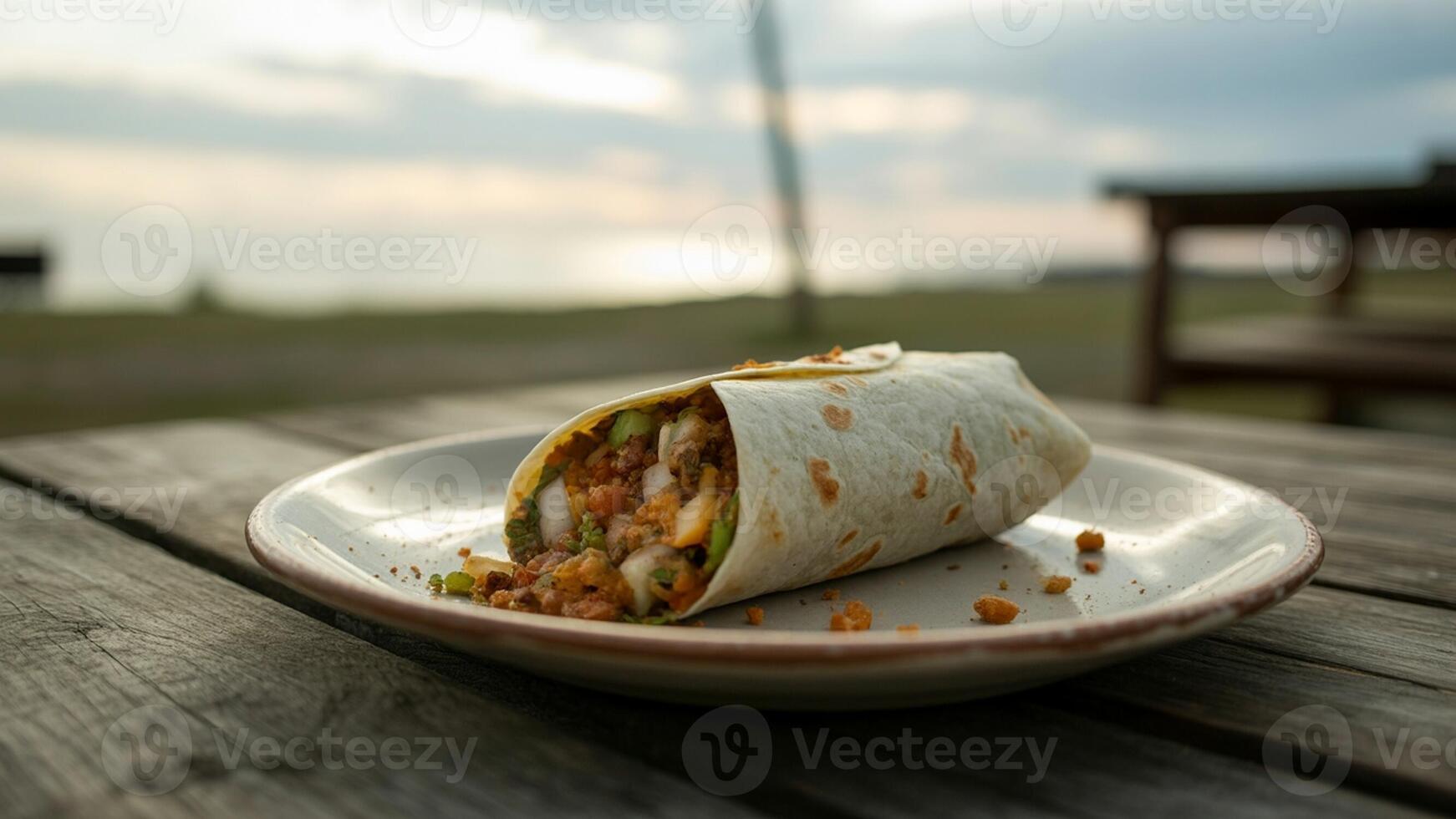A delicious looking burrito served on a plate on a wooden table with a scenic background view outdoors photo