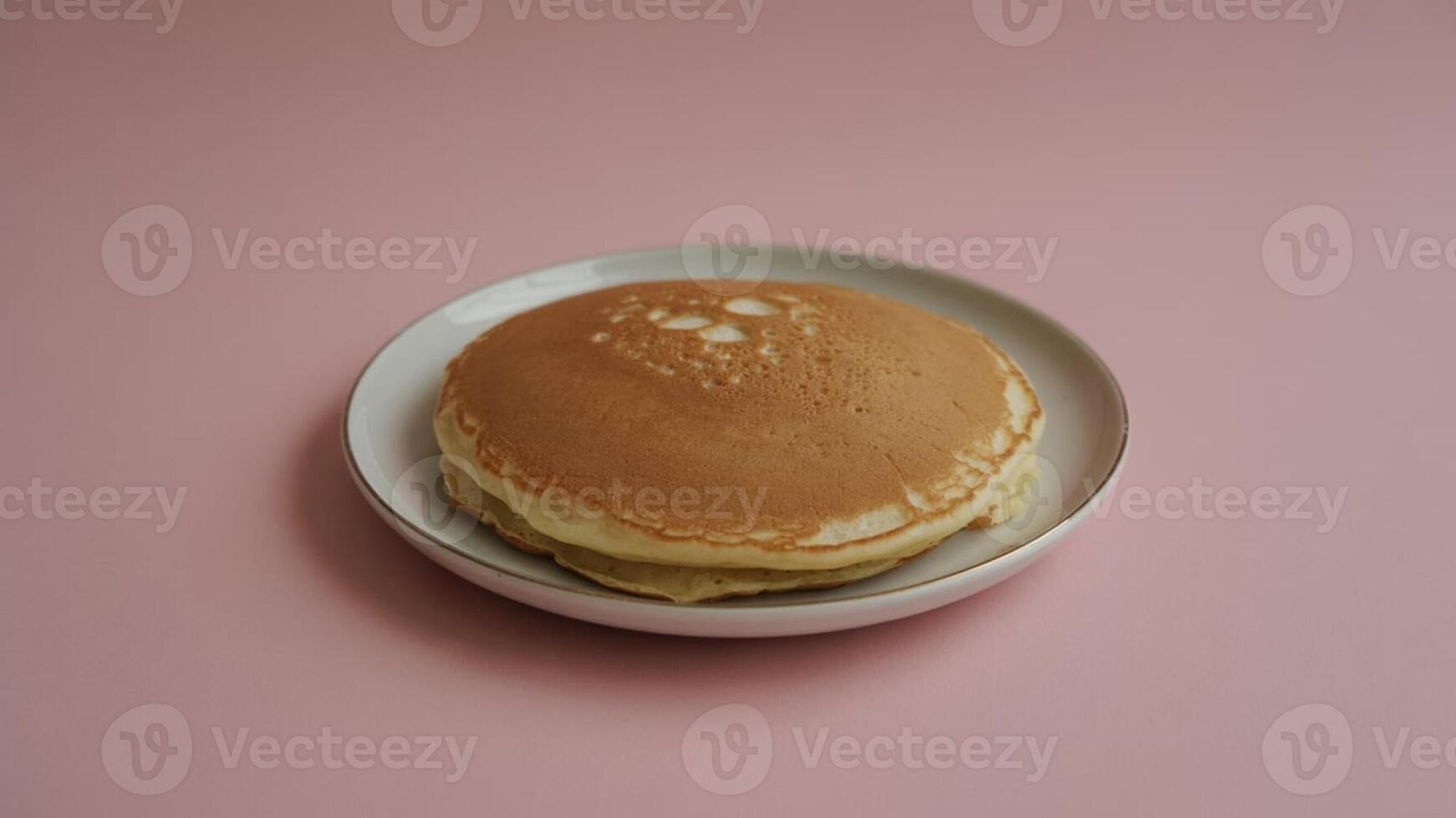 Stack of pancakes on a white plate against a pink background in a minimalist and clean composition photo