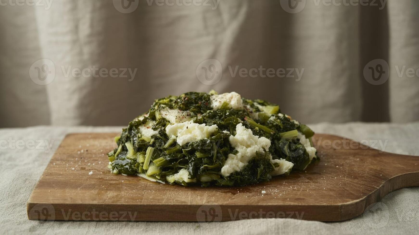 Close up of cooked greens and cheese on a wooden cutting board with a neutral background setting scene photo