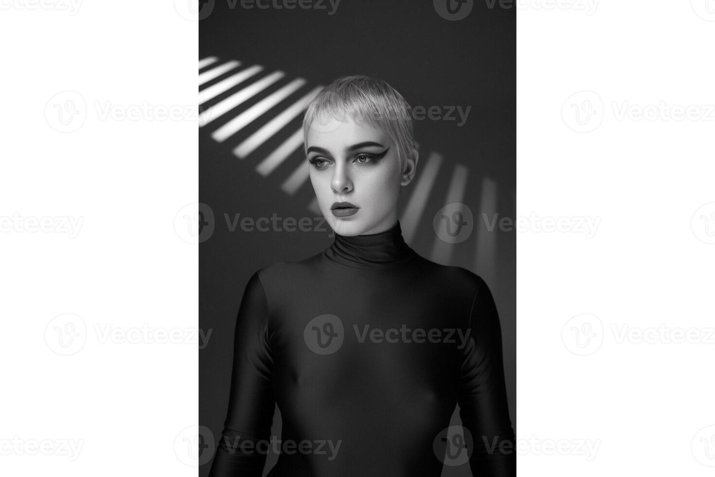 Monochrome portrait of a woman with short hair and dramatic eye makeup looking away photo