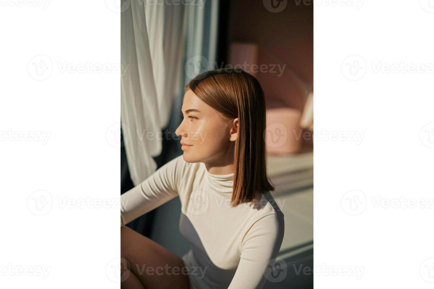 Woman in white turtleneck sitting near window with sunlight casting shadows indoors photo