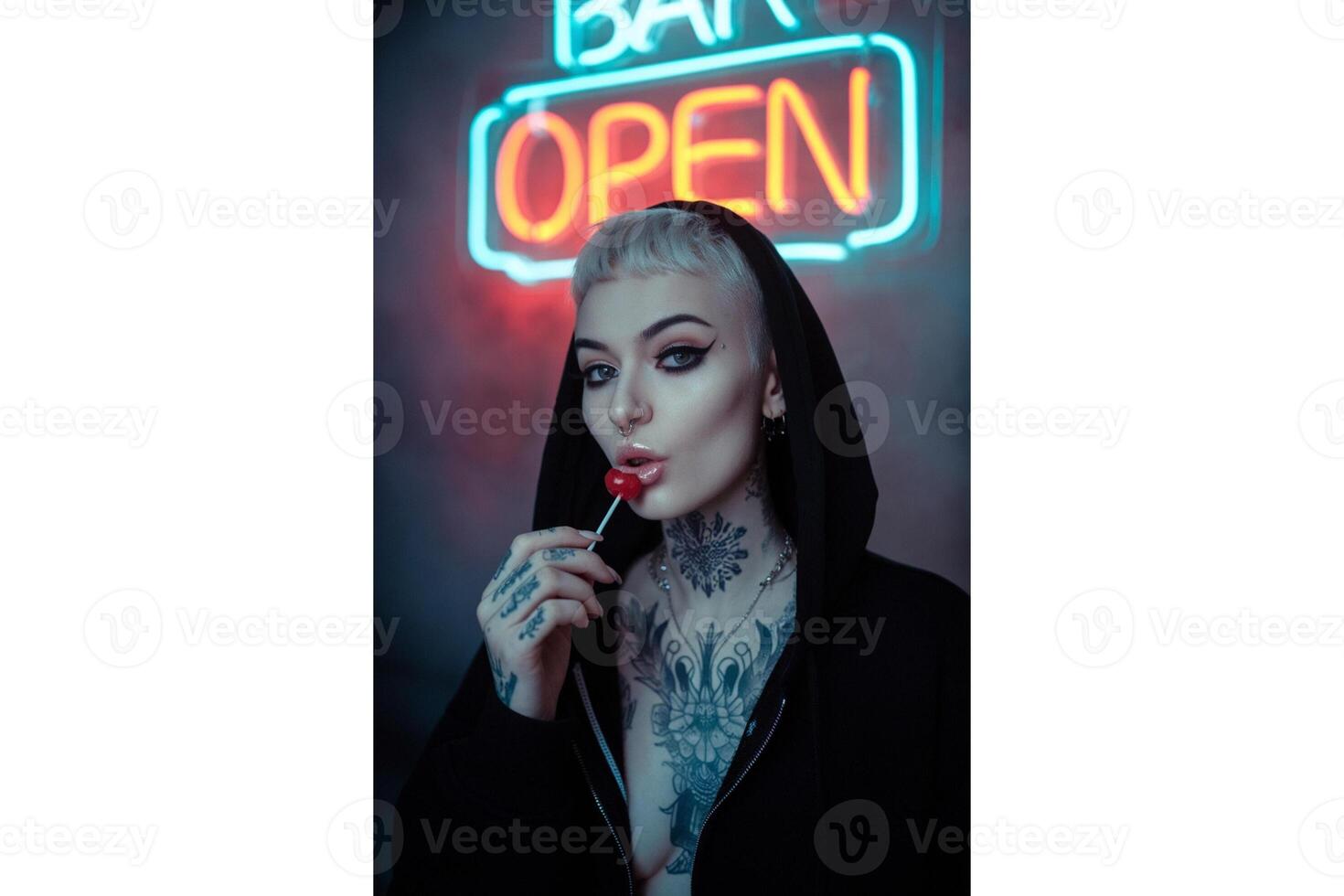 Woman with tattoos and lollipop posing in front of a neon open bar sign light photo