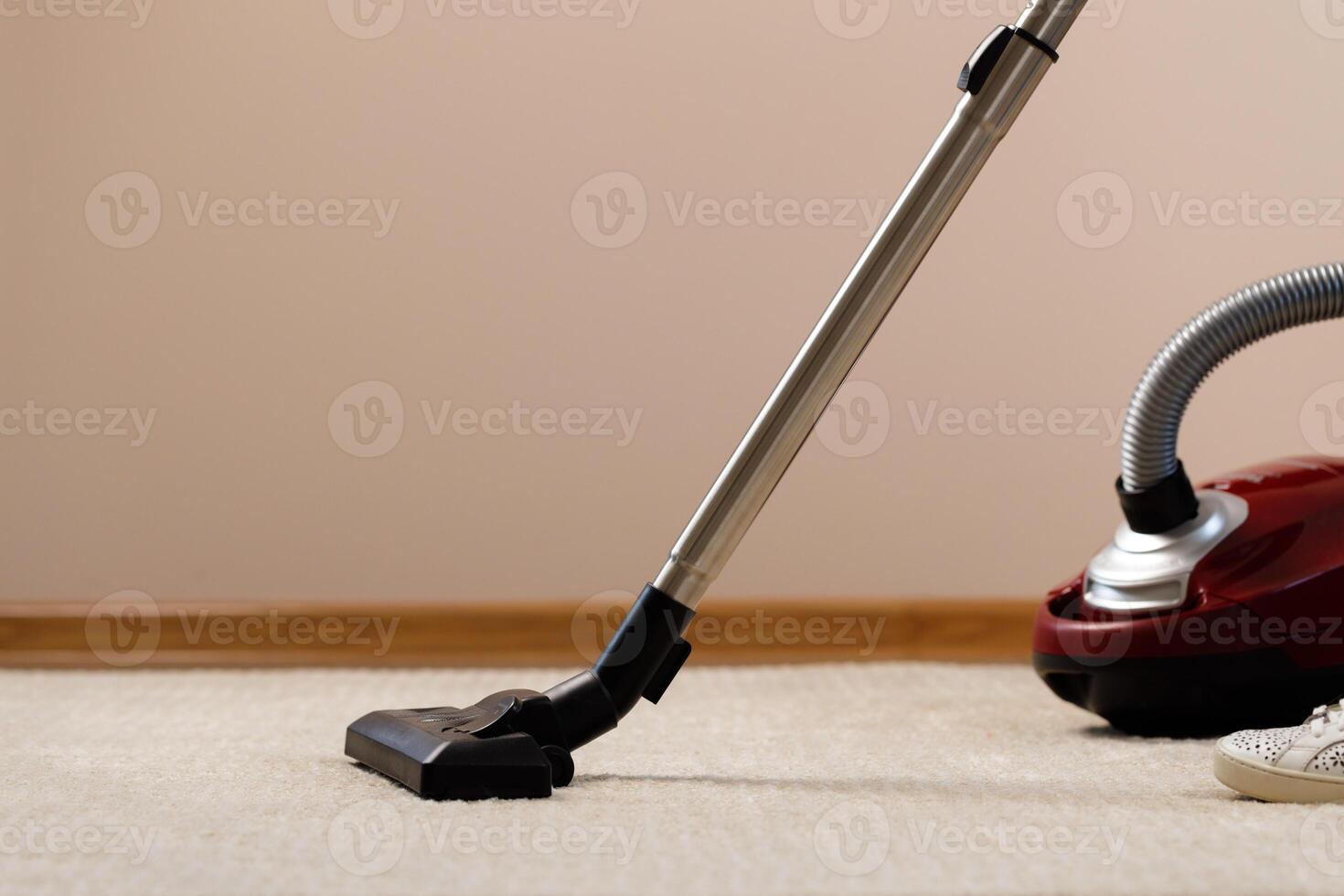 Red vacuum cleaner on a beige carpet photo