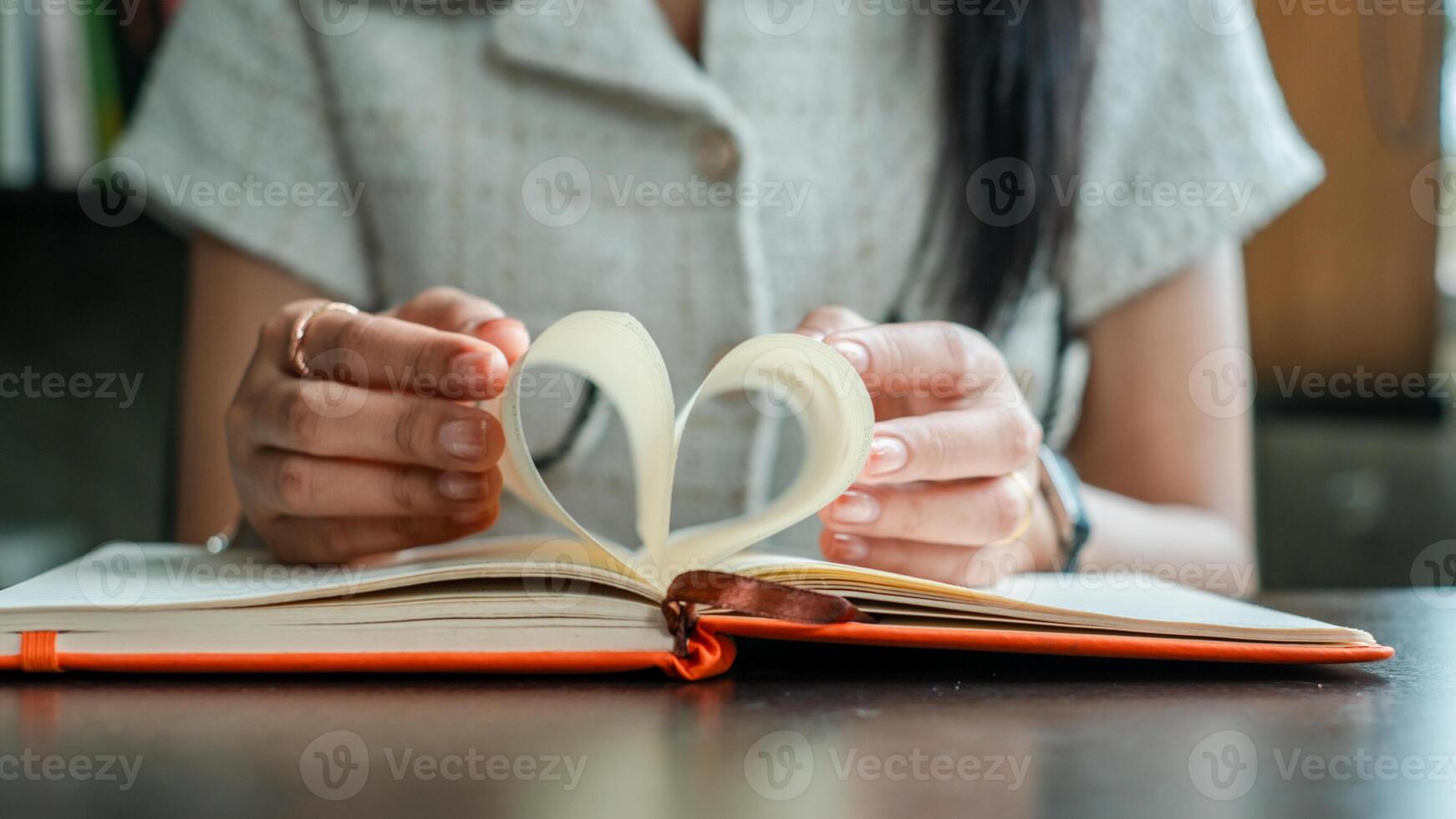 Close-up of hands forming a heart shape with book pages, symbolizing love for reading and literature. photo