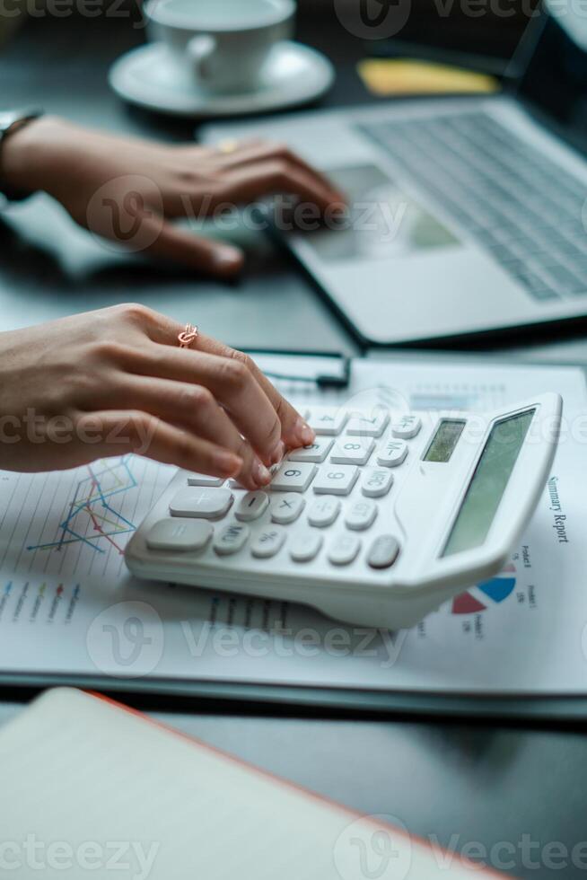 Close-up of hands using a calculator and laptop, analyzing financial data in a modern office environment. photo