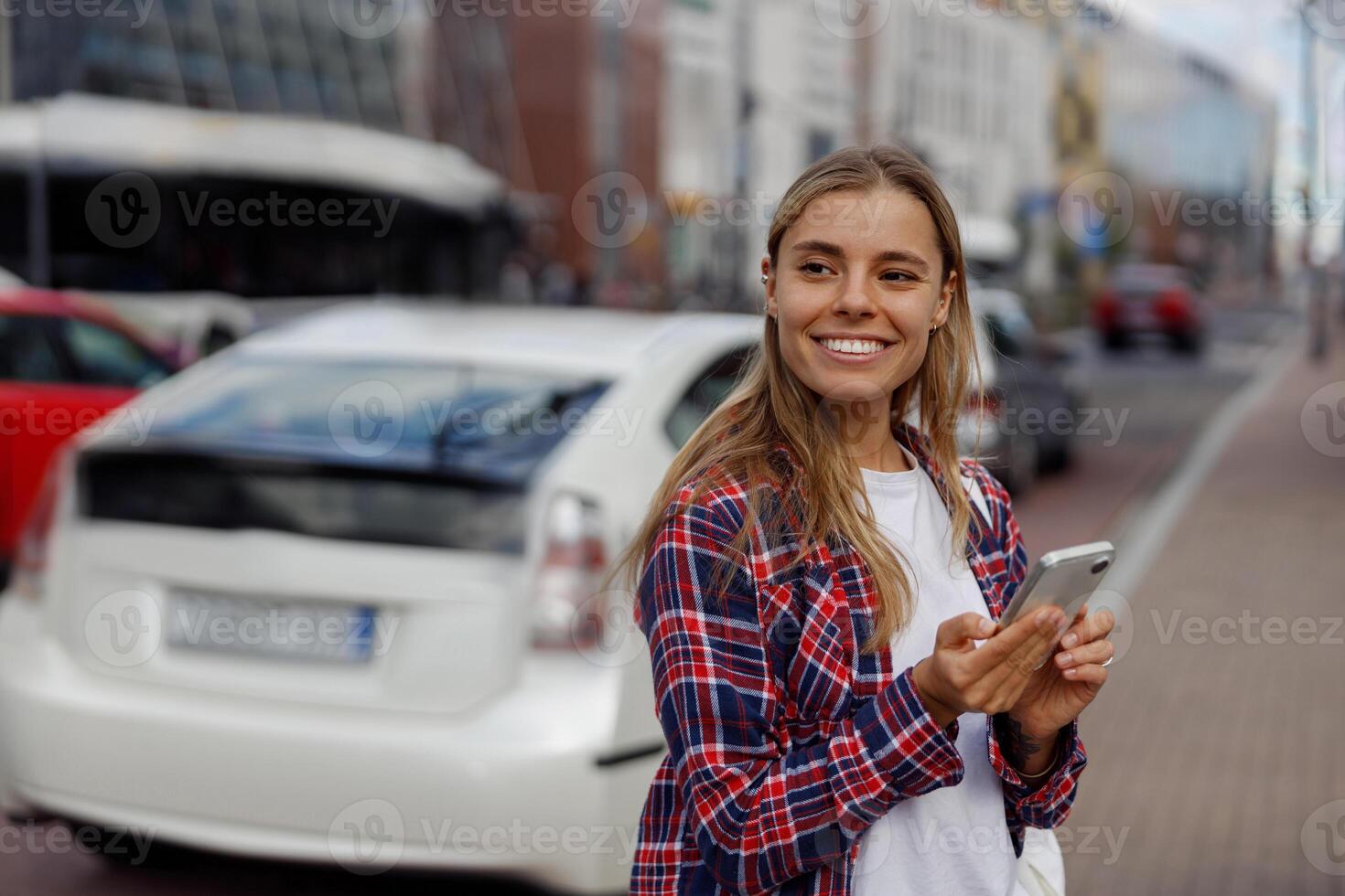 A young woman happily smiling while texting on her smartphone in an urban city setting photo